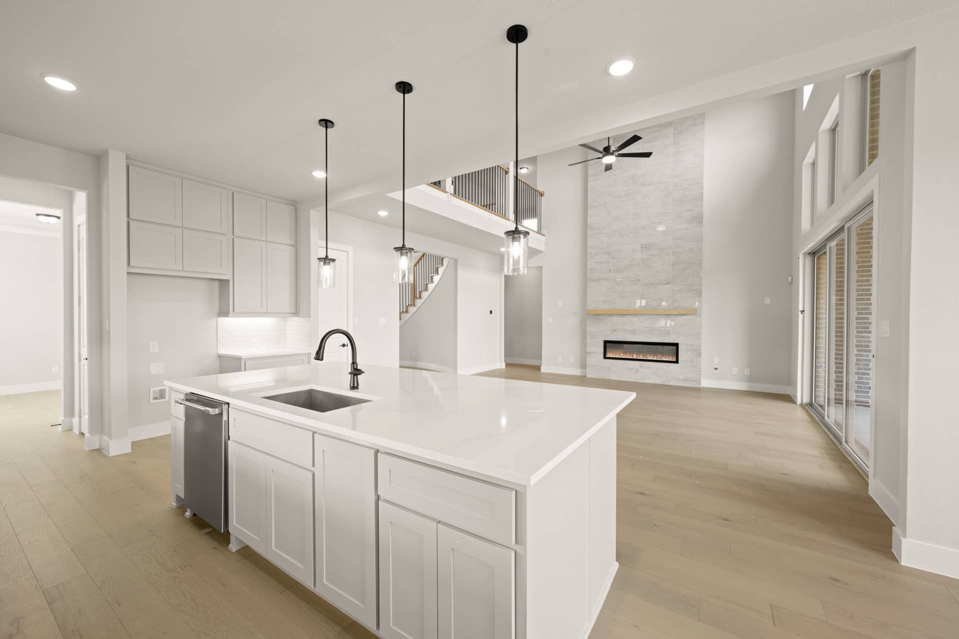 Spacious modern kitchen with island, pendant lights, and open living area.