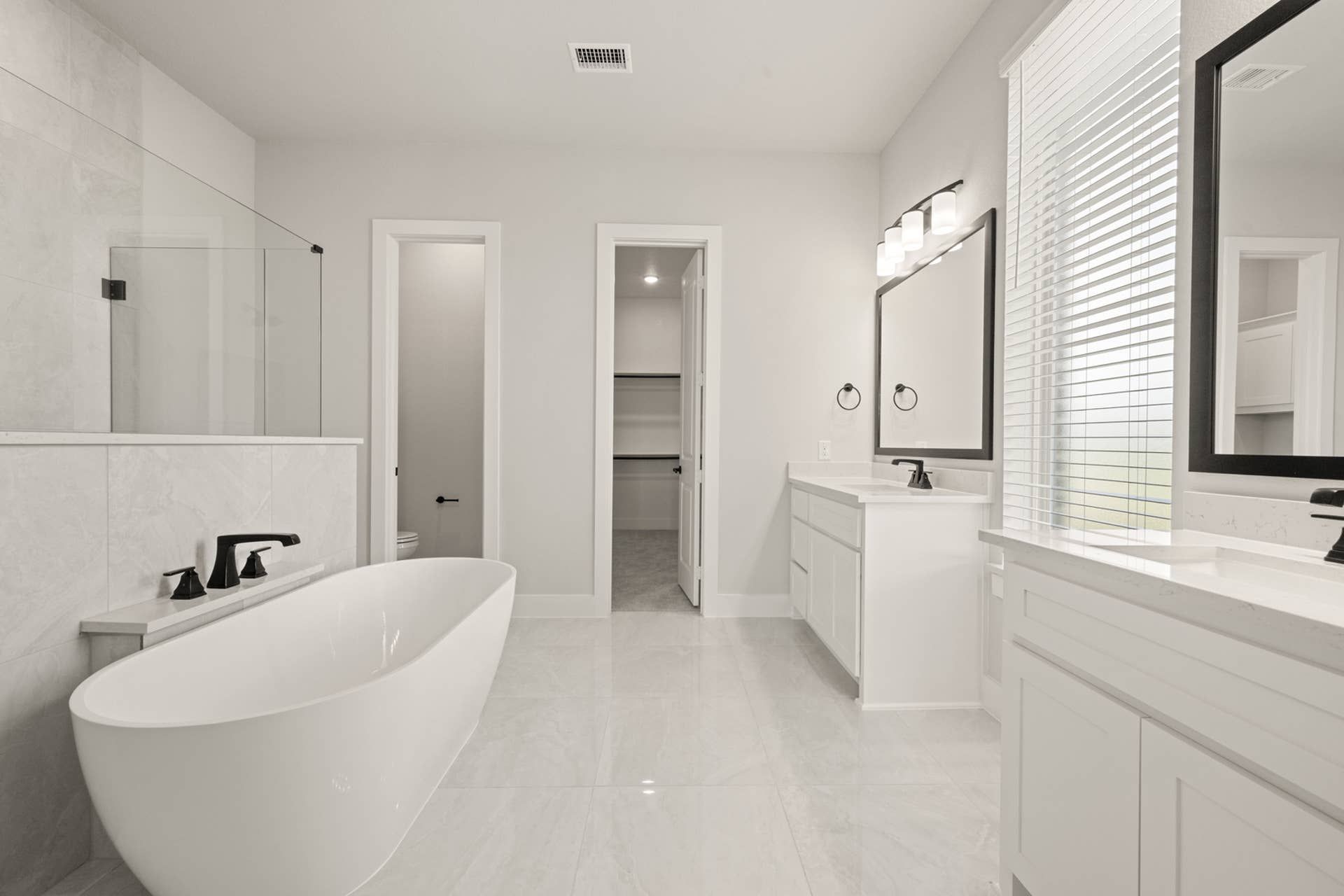 Luxurious bathroom with freestanding tub, double vanity, and walk-in closet.