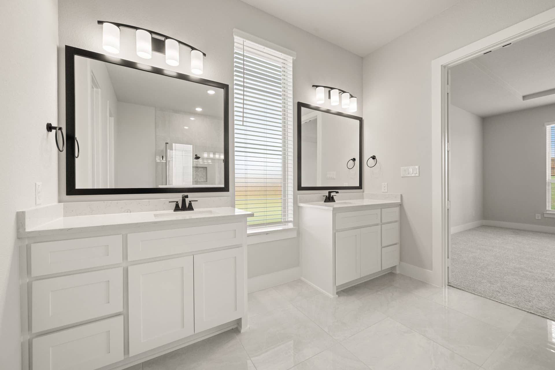Spacious primary suite bathroom with dual vanities and modern lighting fixtures.