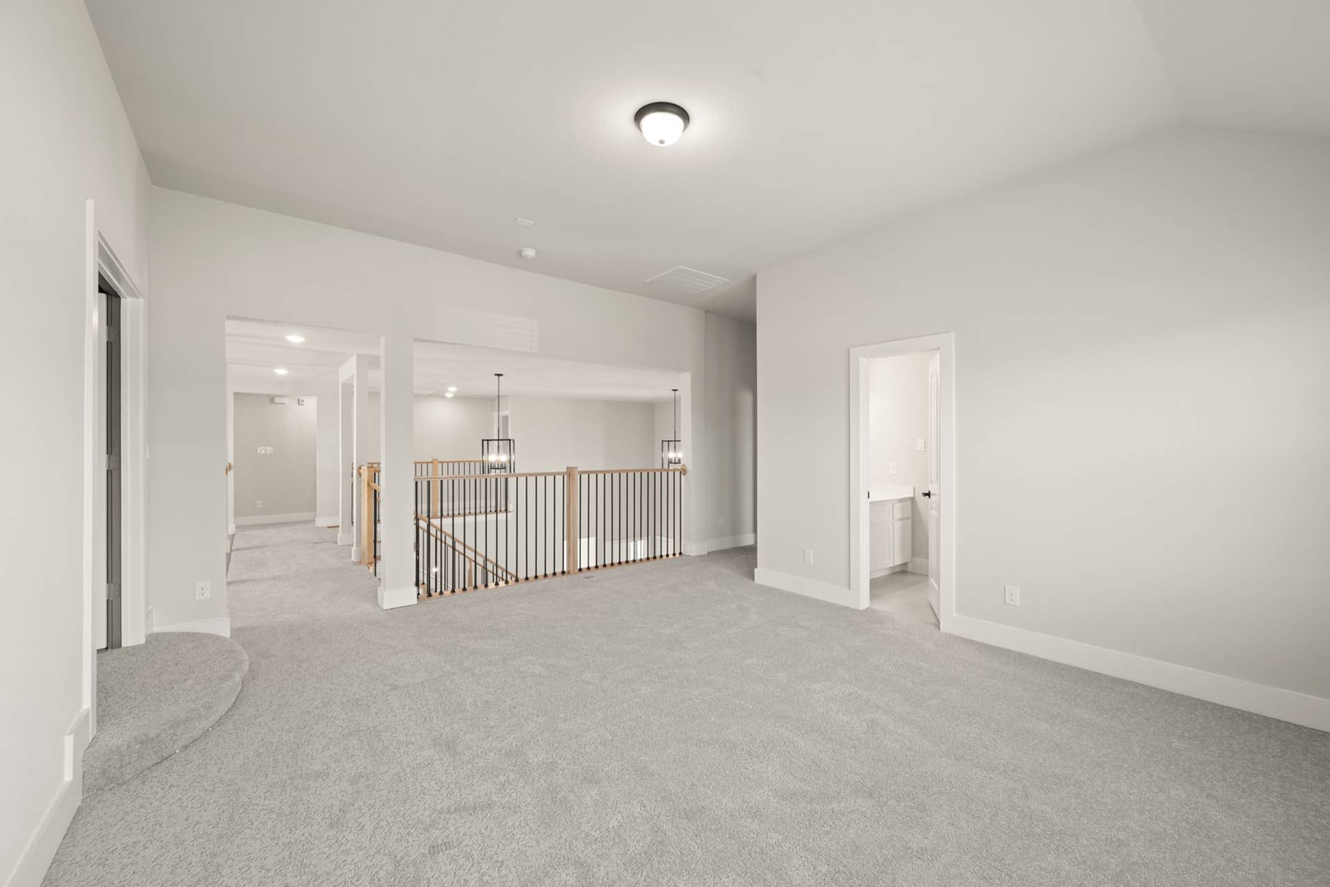 Spacious game room with neutral decor and open railing overlooking lower level.
