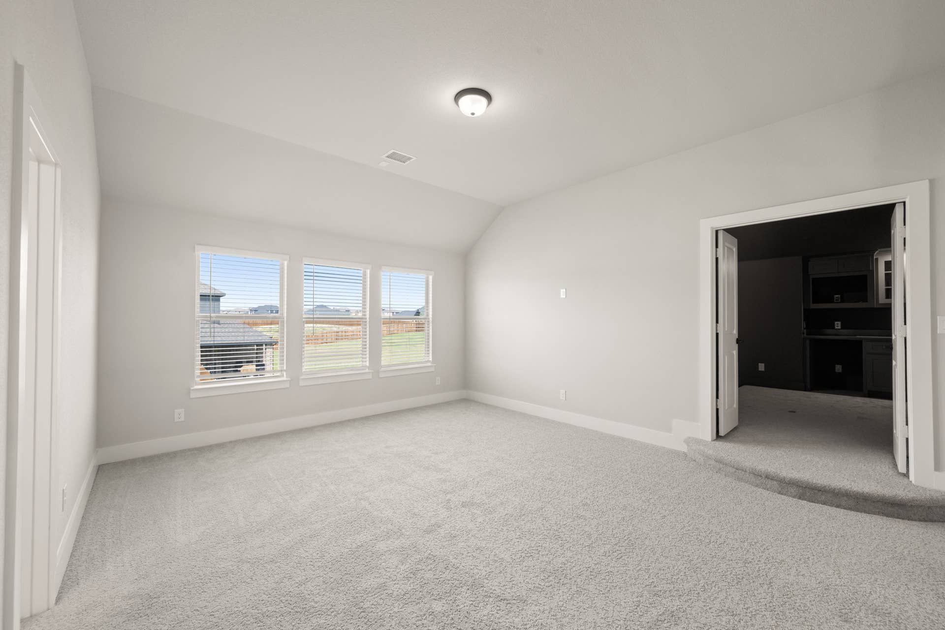 Spacious game room with carpet flooring and large windows.