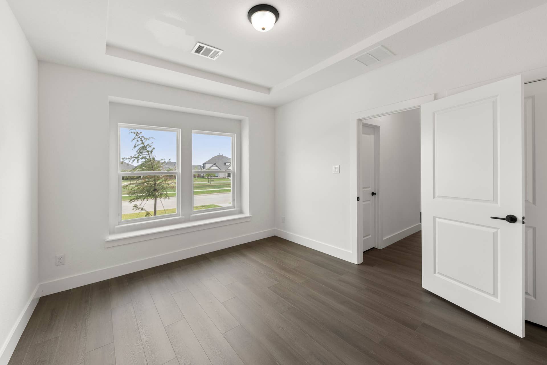 Bright study room with hardwood floors and large windows overlooking the street.