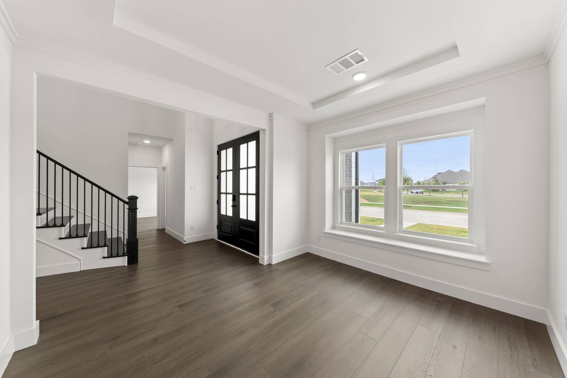Bright dining area with wood floors, large windows, and staircase view.