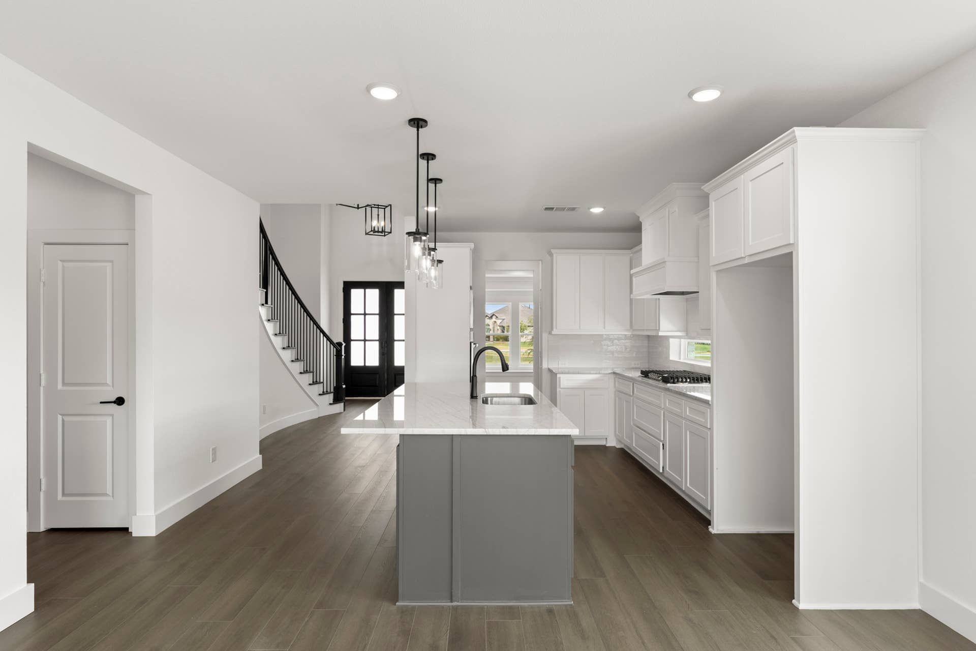 Modern kitchen with island, white cabinetry, and dark wood flooring.