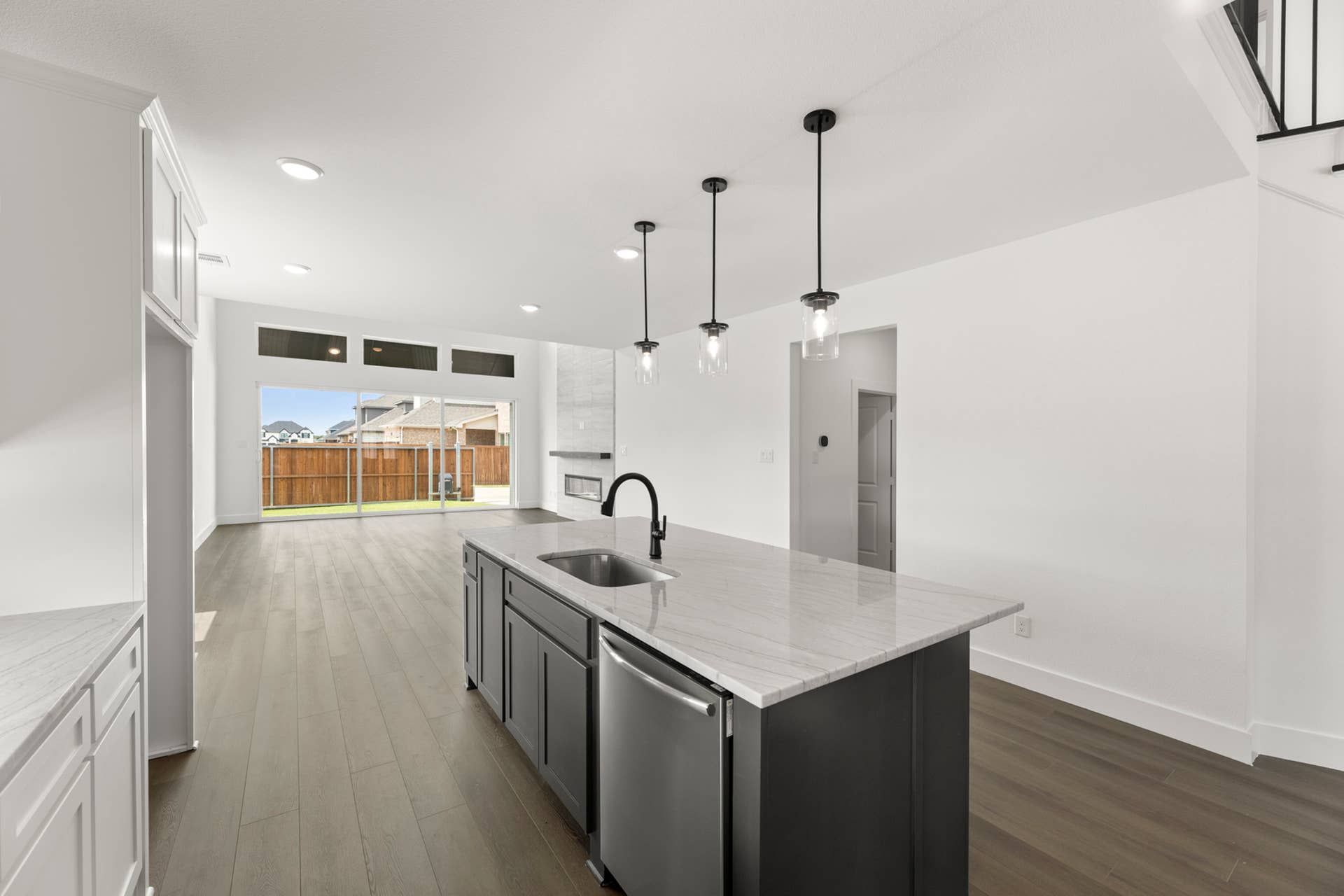Modern kitchen with island, pendant lighting, and large sliding glass doors.