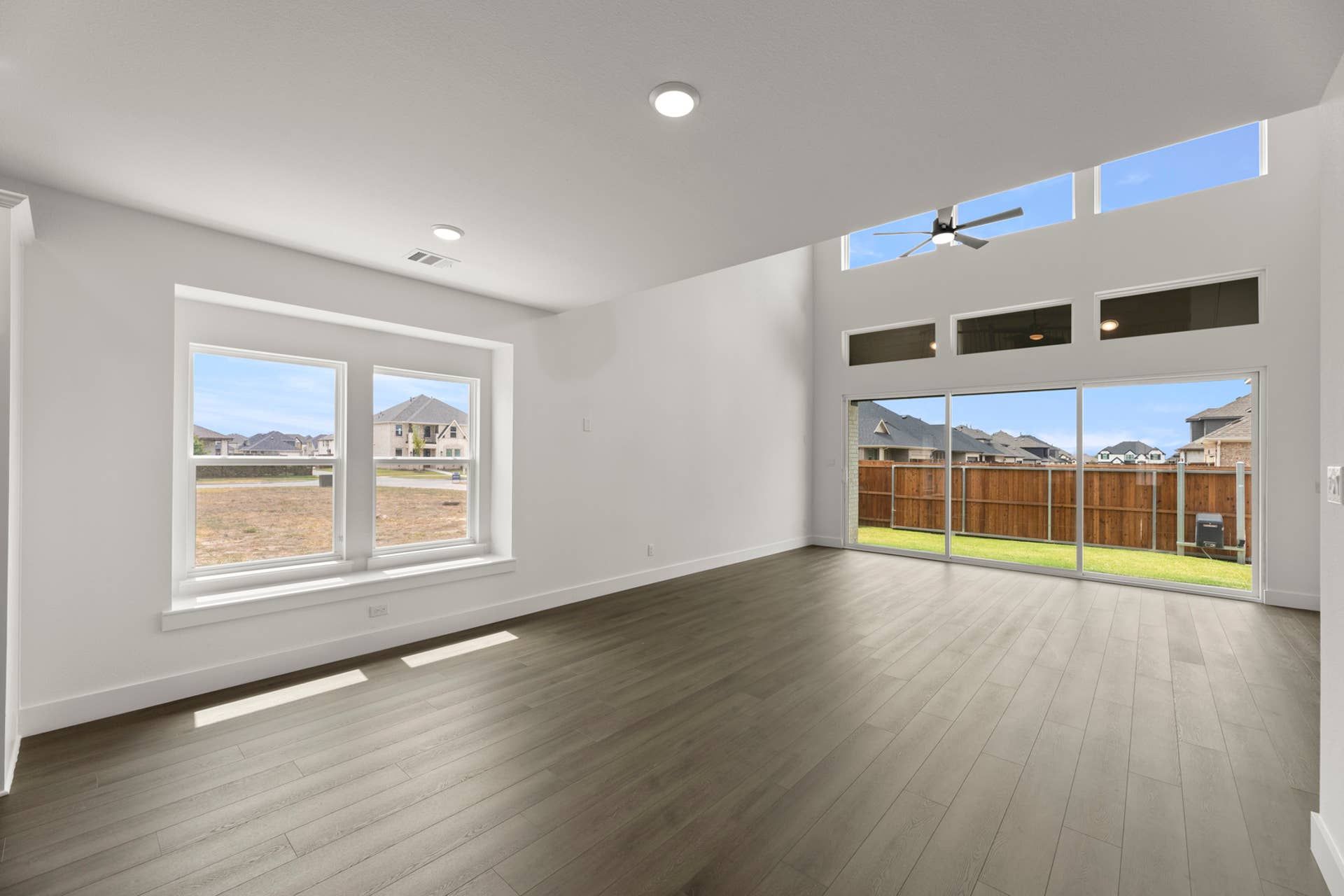 Spacious modern living room with large windows and wooden flooring.