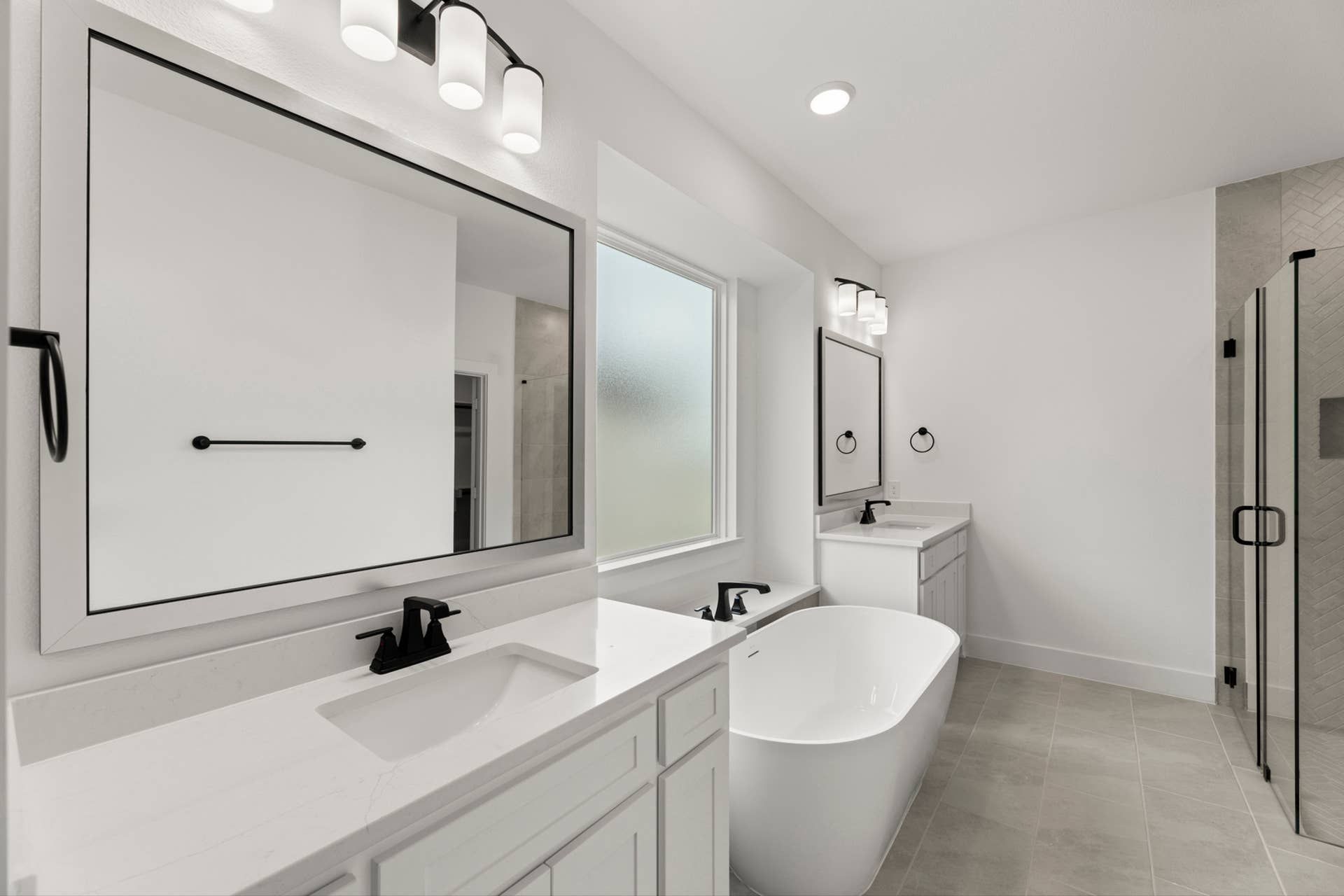 Spacious modern bathroom with double sinks, freestanding tub, and glass shower enclosure.