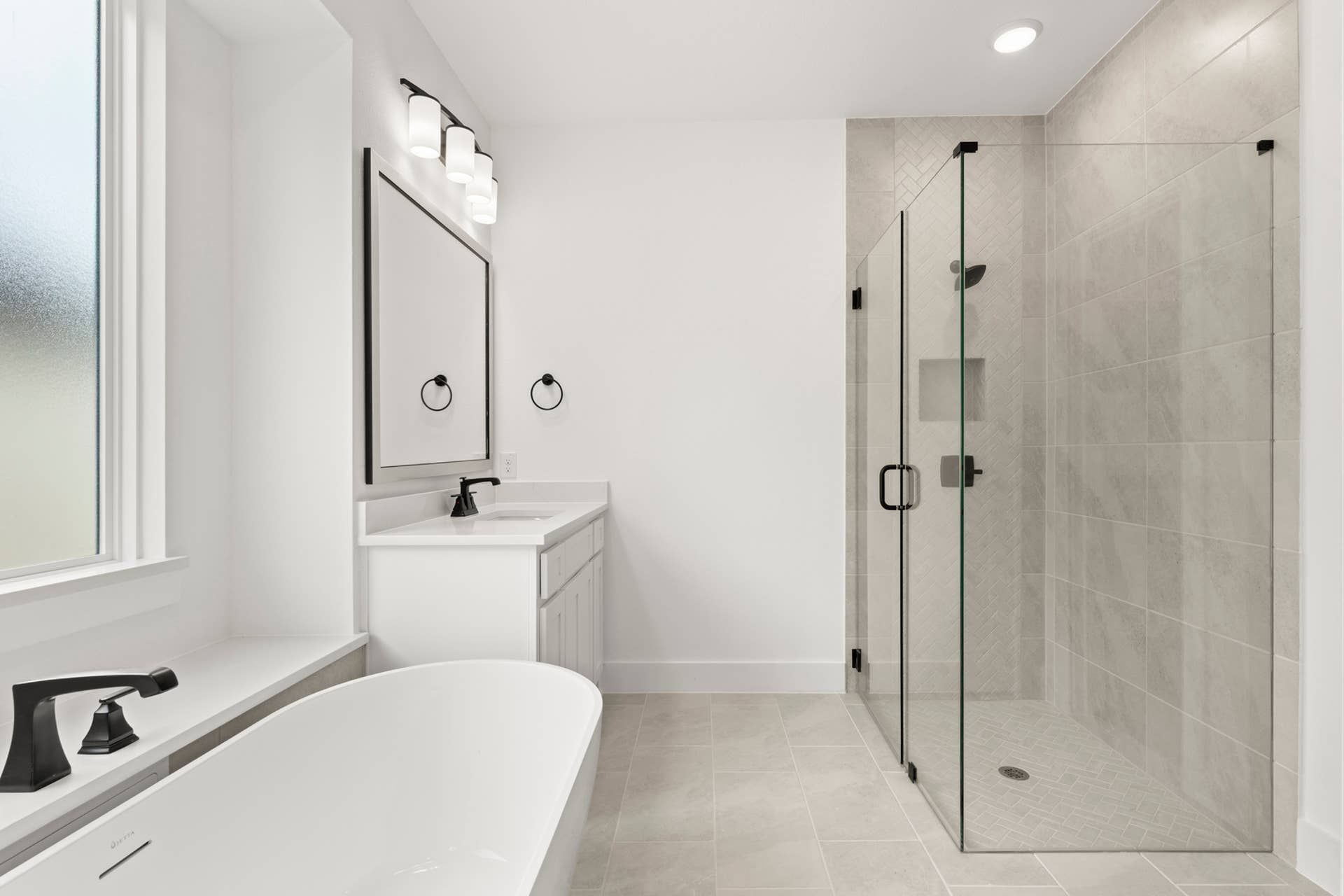 Modern bathroom with glass shower, freestanding tub, and dual vanity.