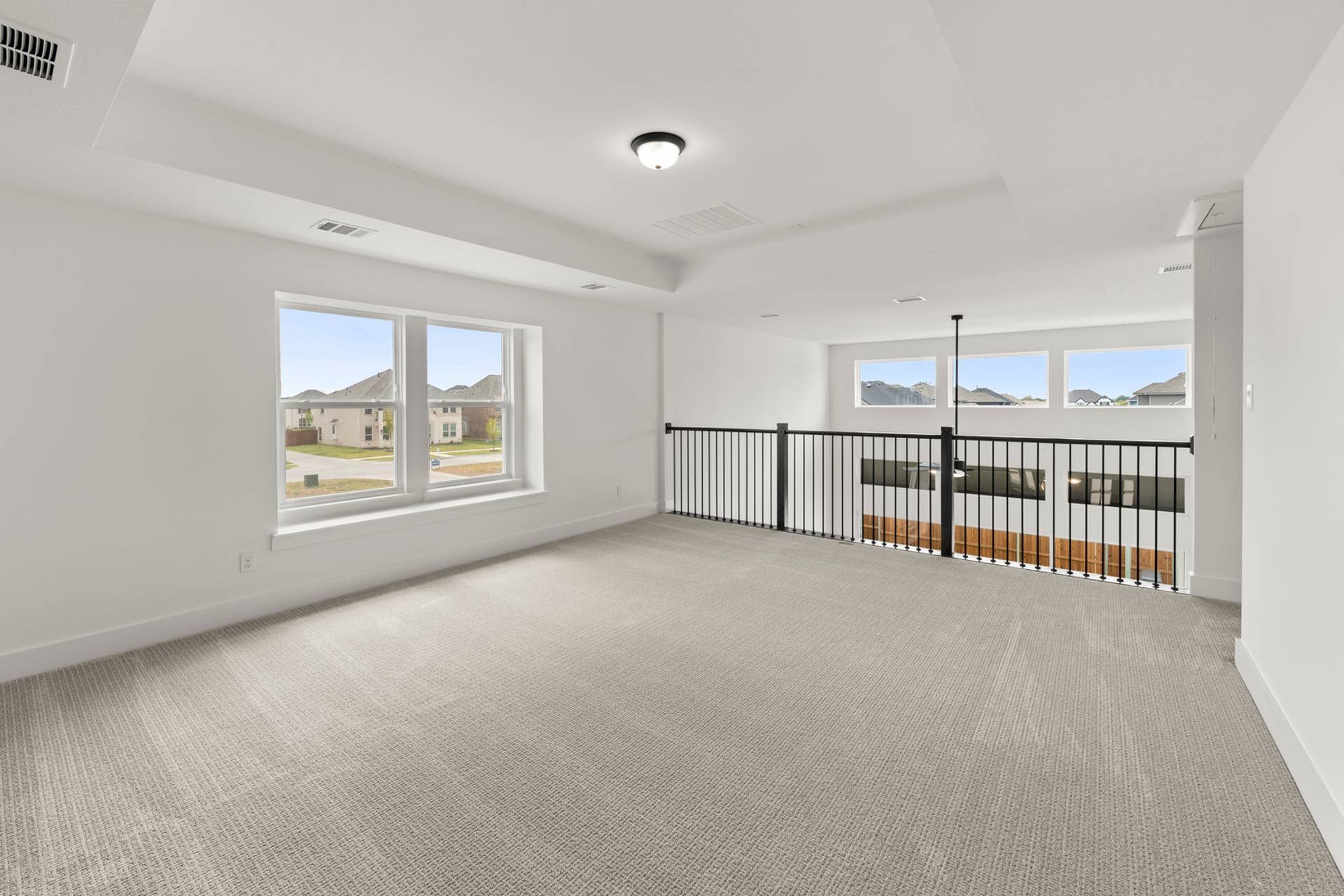 Spacious interior loft with large windows and railing overlooking lower level.