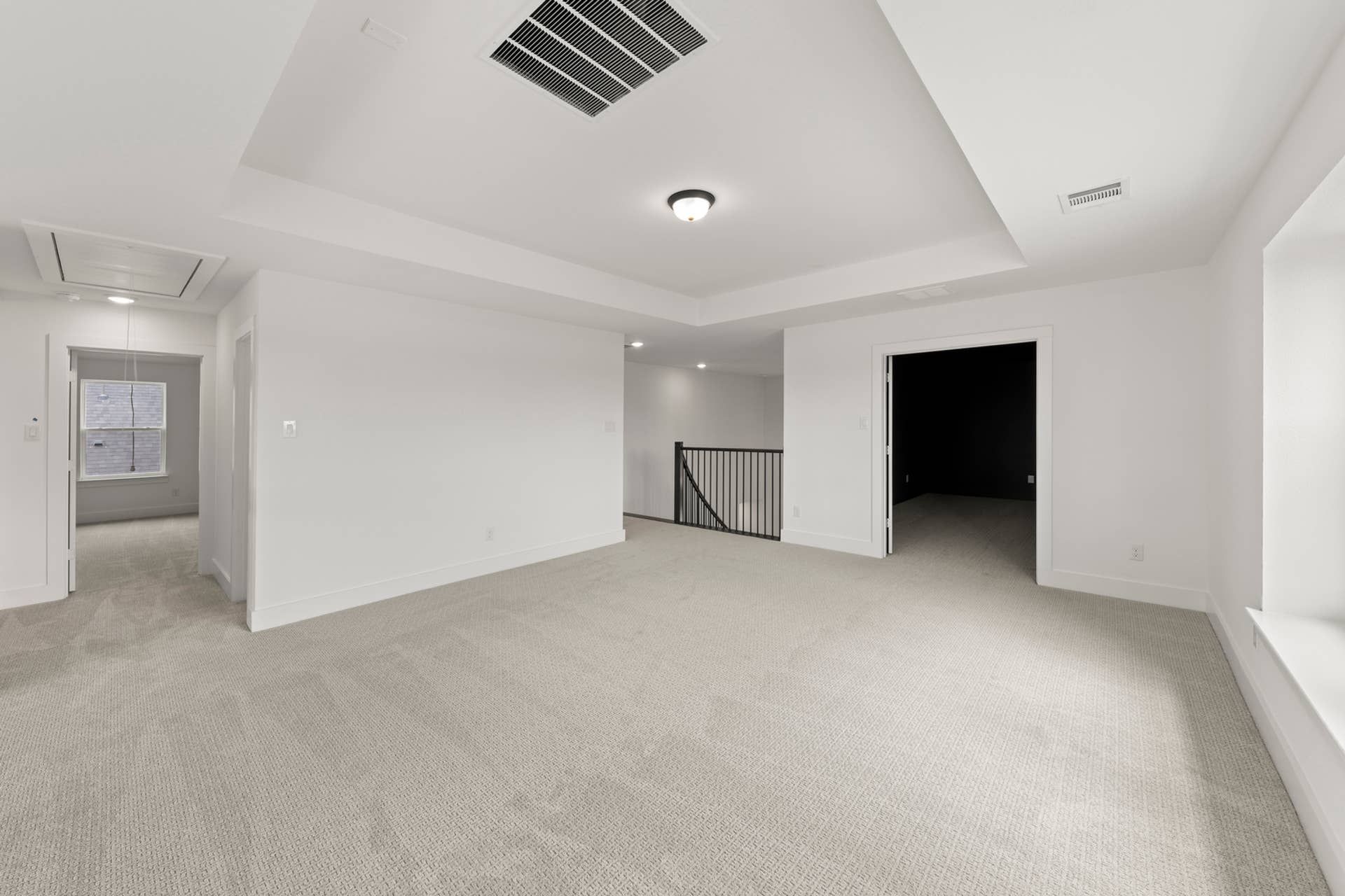 Spacious carpeted interior with tray ceiling and recessed lighting.