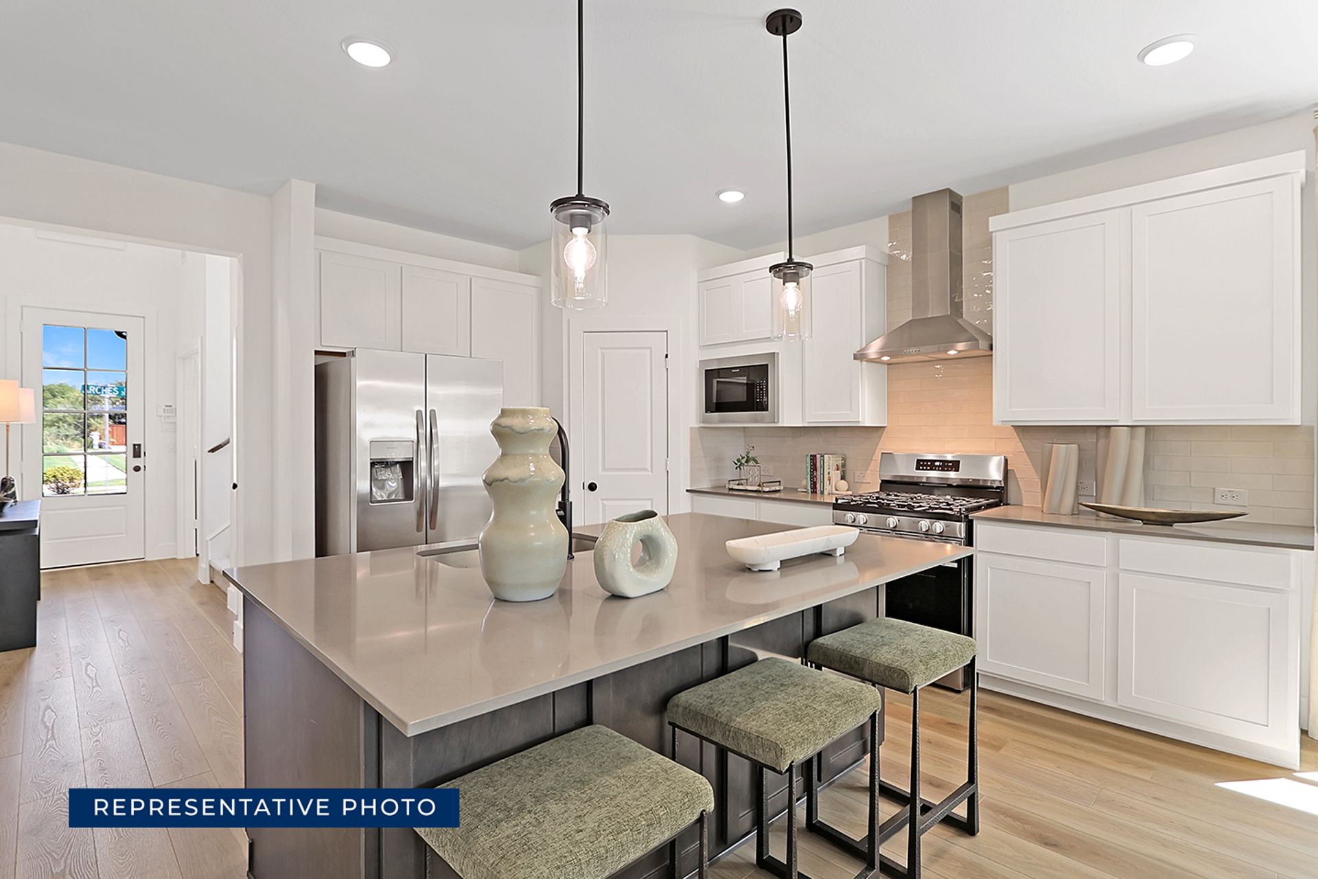 Modern kitchen with island, stainless steel appliances, and pendant lighting.