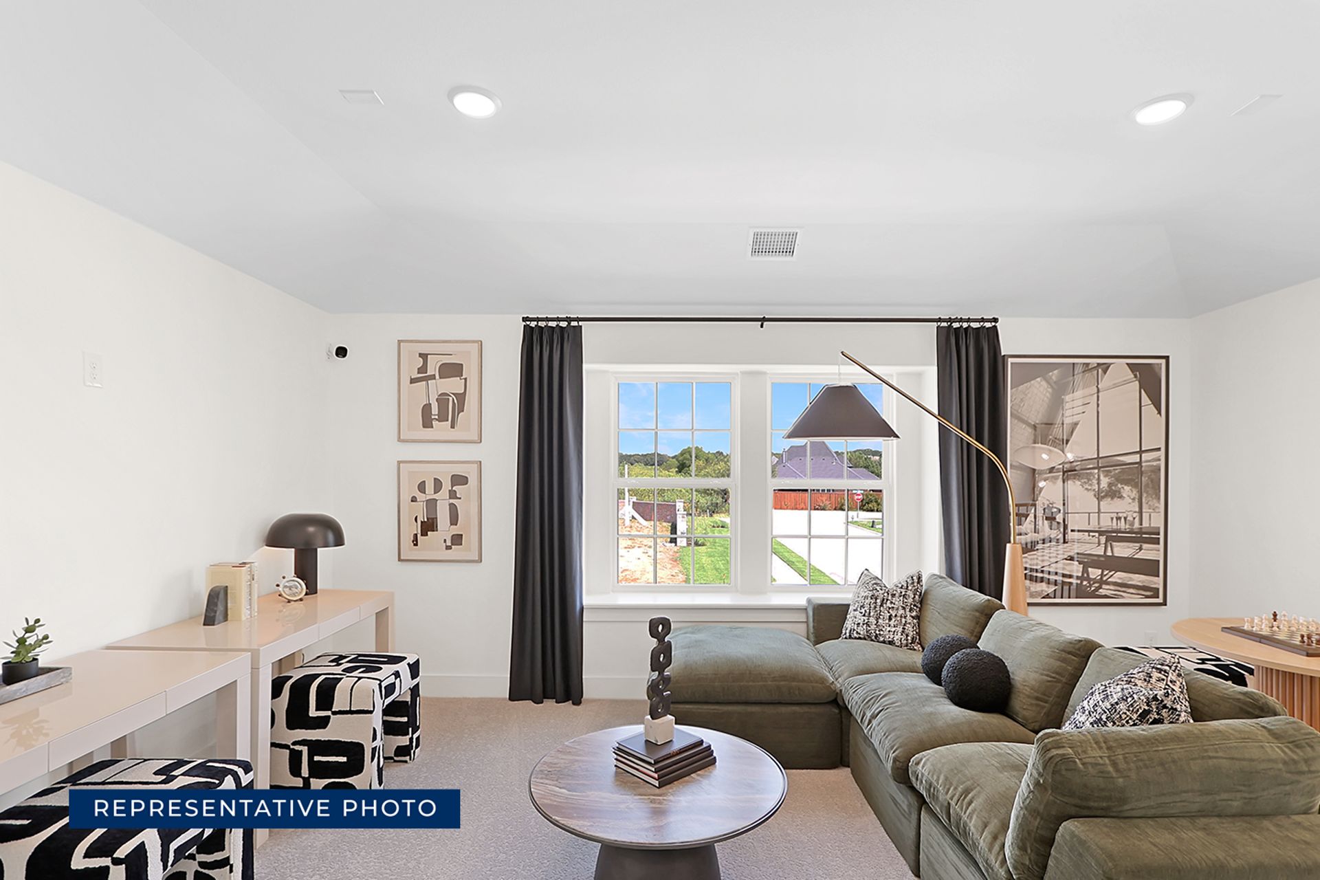 Modern living room with green sectional sofa, abstract art, and large window view.