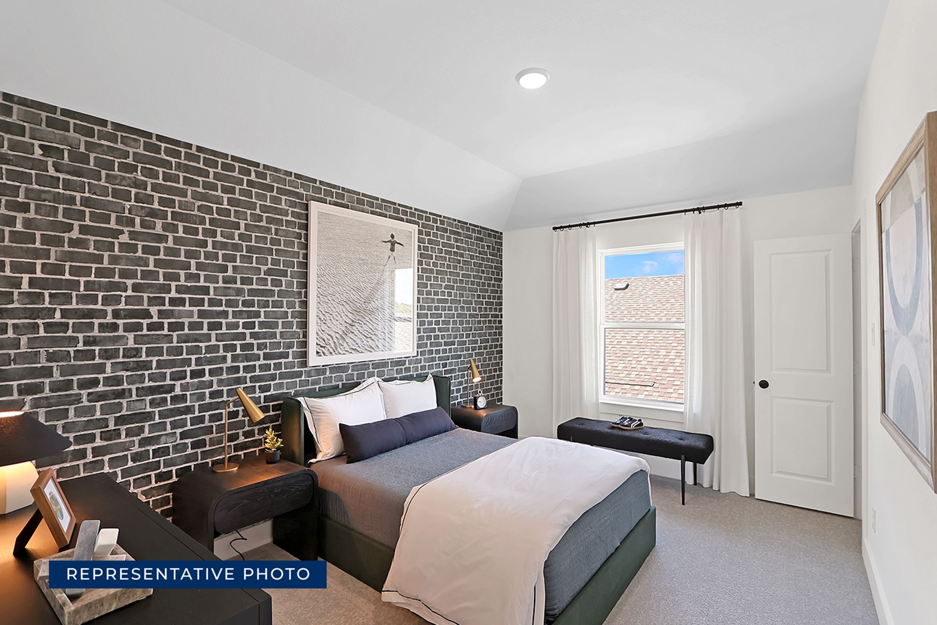 Modern bedroom with brick accent wall and large window.