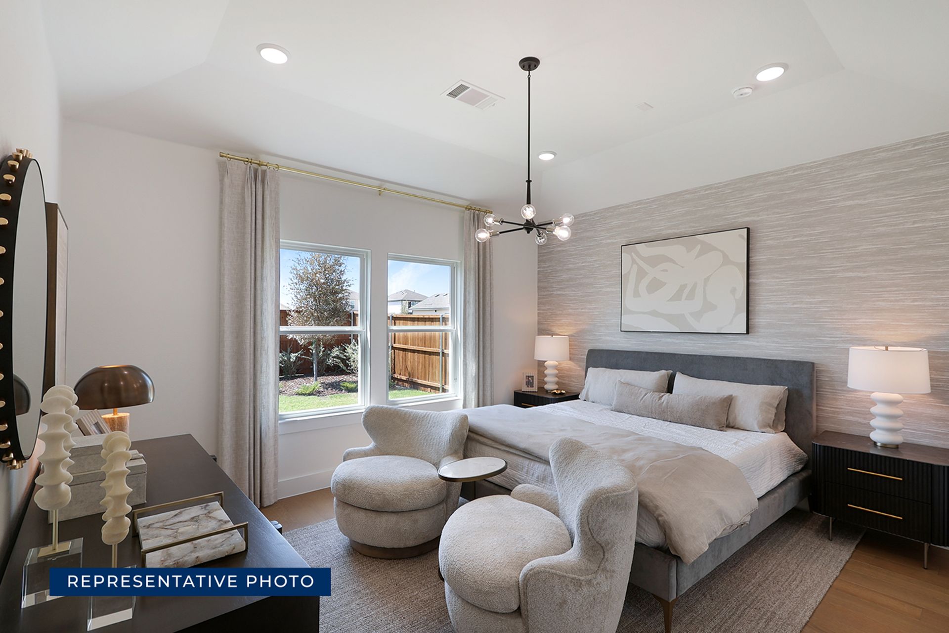 Modern bedroom with gray decor, large bed, and armchairs near window.