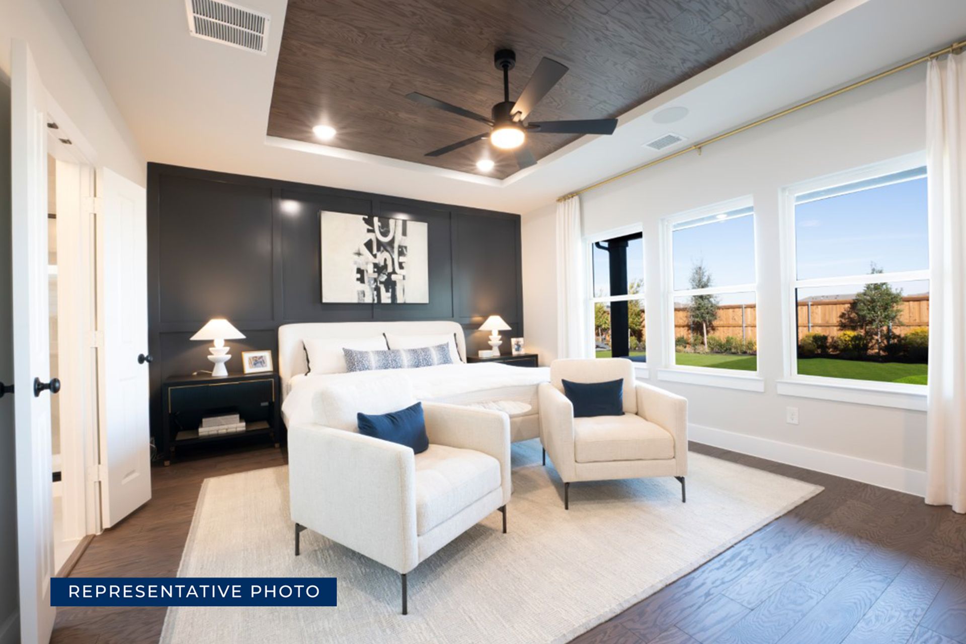 Modern bedroom with large windows, cozy seating, and elegant decor.
