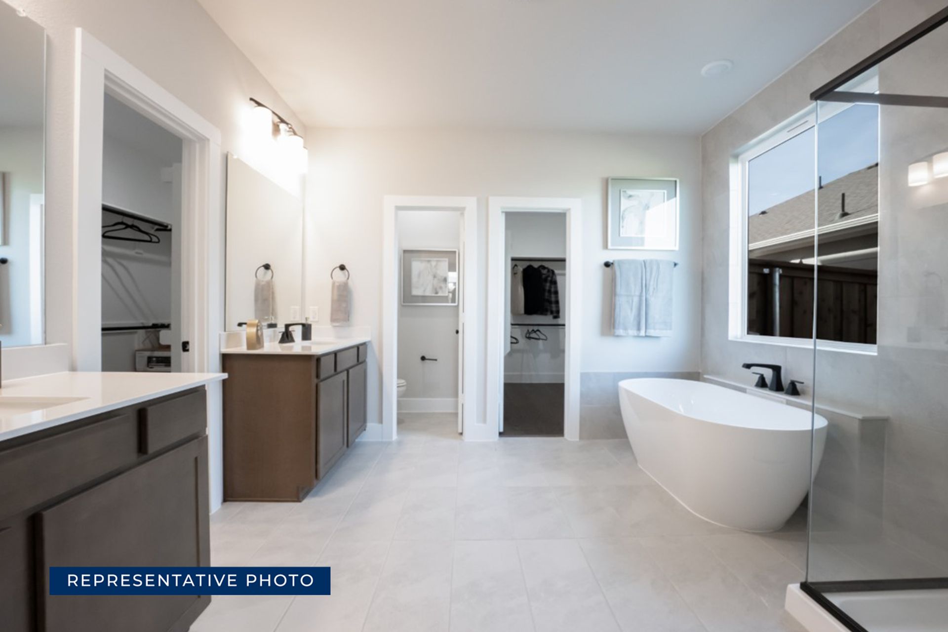 Modern bathroom with freestanding tub, double vanity, and walk-in closets.