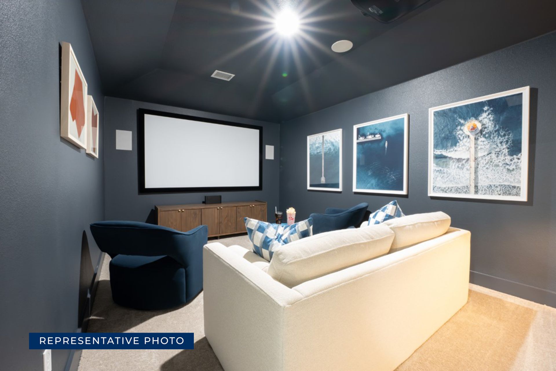 Home theater room with sofa, armchairs, and large screen