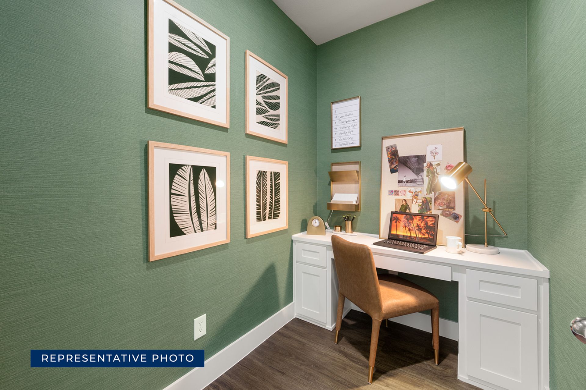 Modern home office with green walls, framed art, and a white desk.