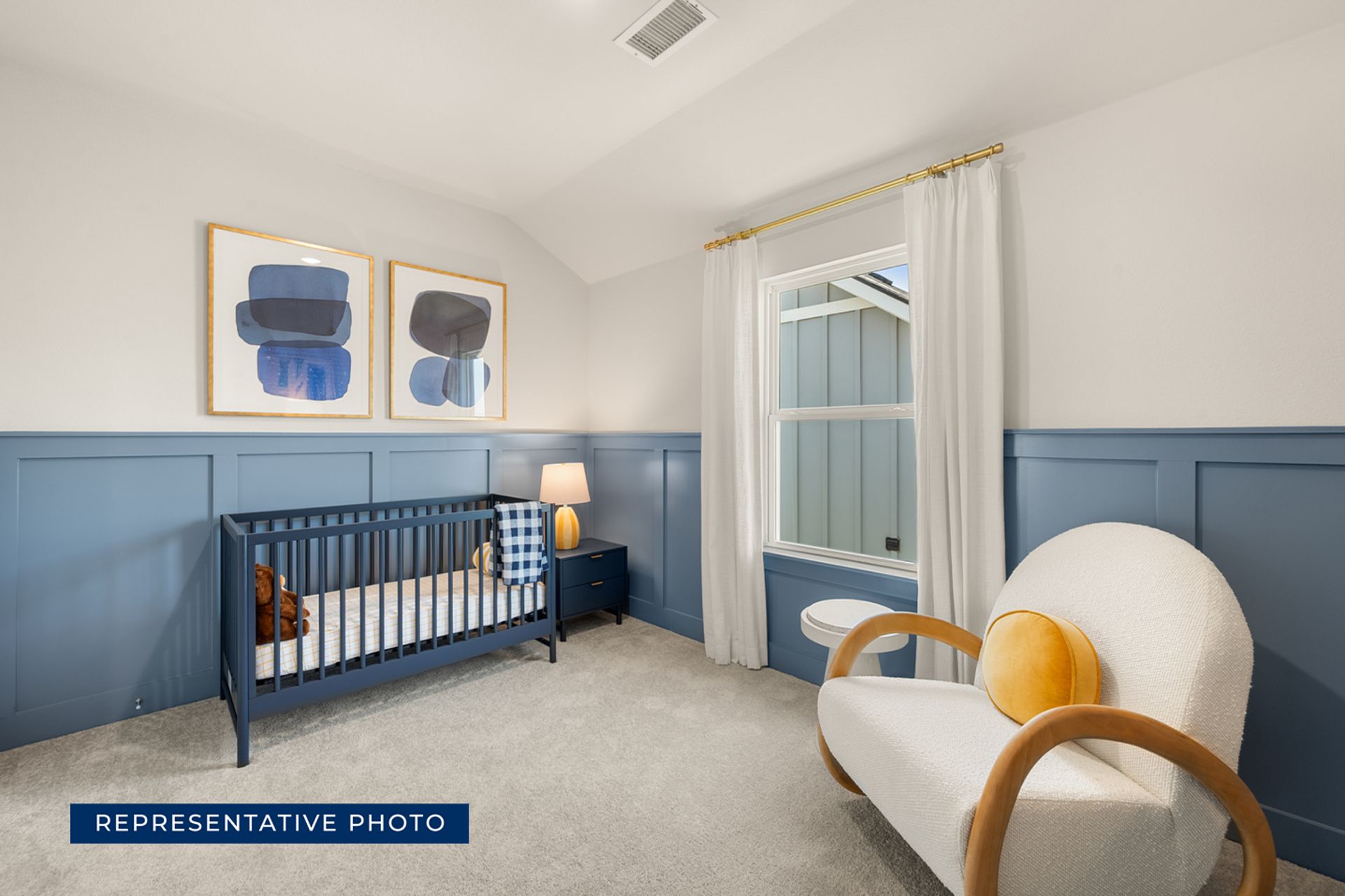 Cozy nursery with blue crib, armchair, and abstract wall art.