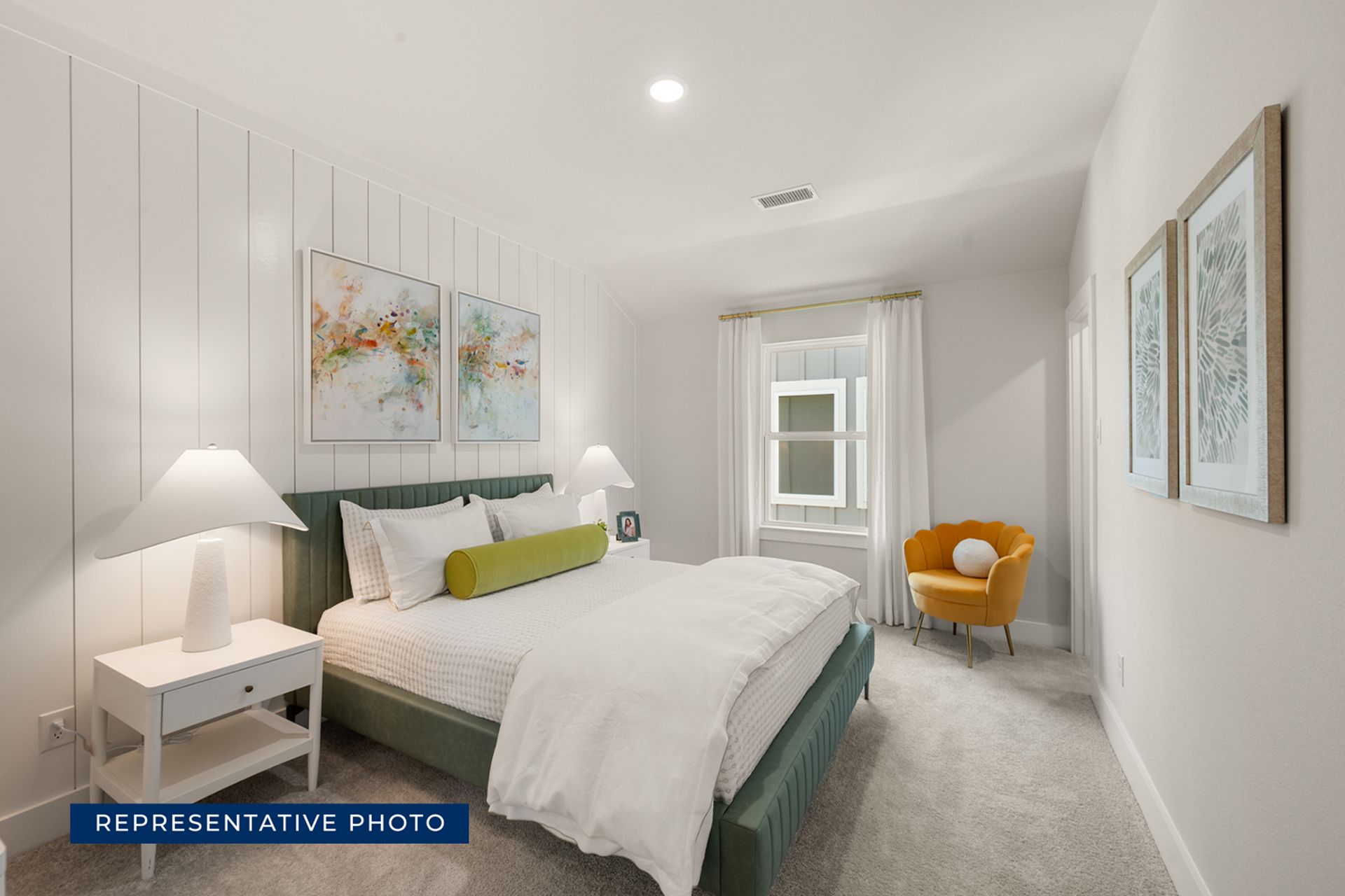 Modern bedroom with white walls, green bed, and colorful artwork.