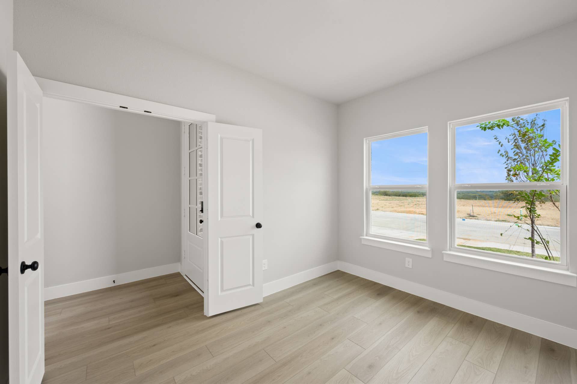 Bright study room with wood flooring and large windows overlooking outdoor landscape.