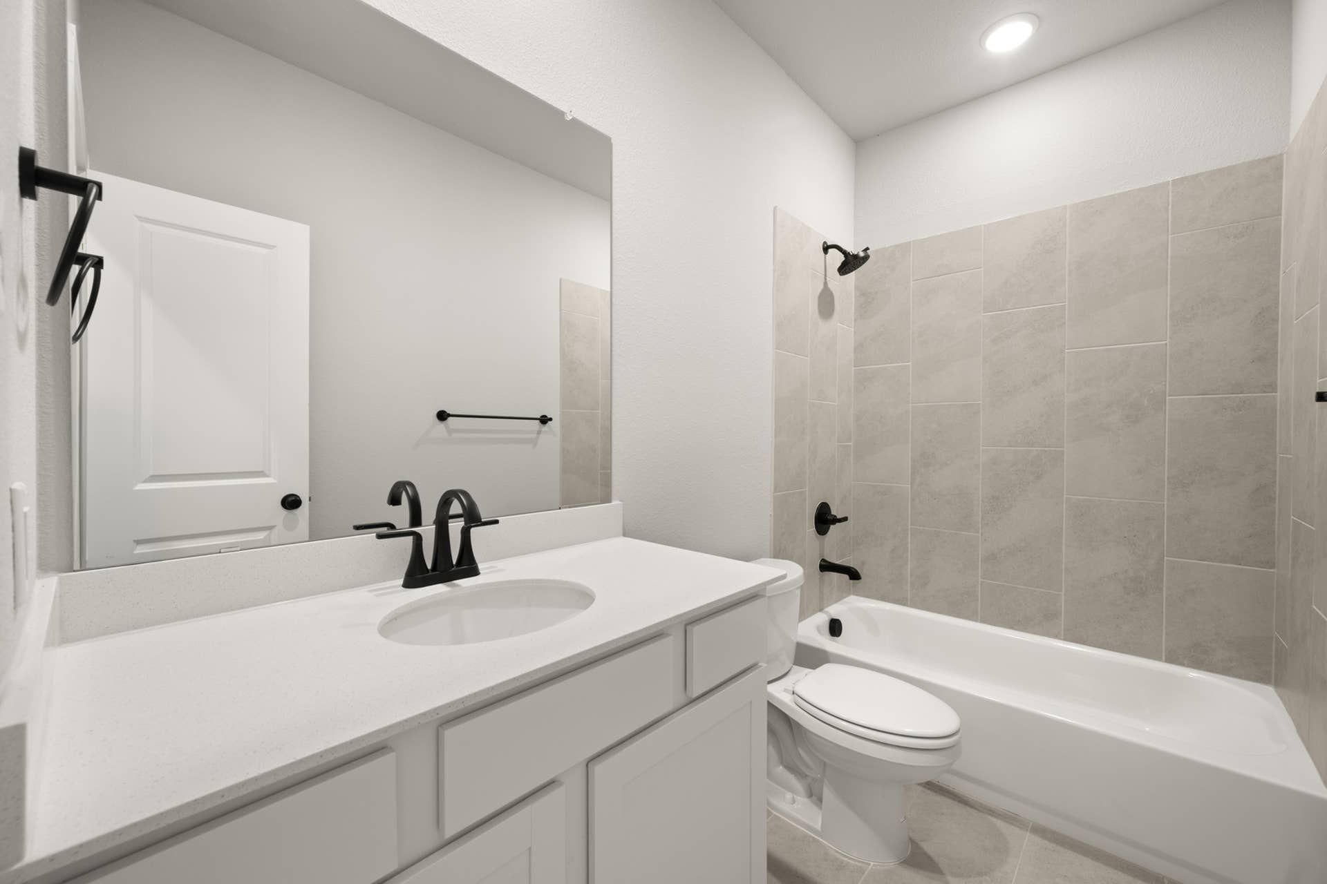 Modern bathroom with white vanity, black fixtures, and tiled shower.