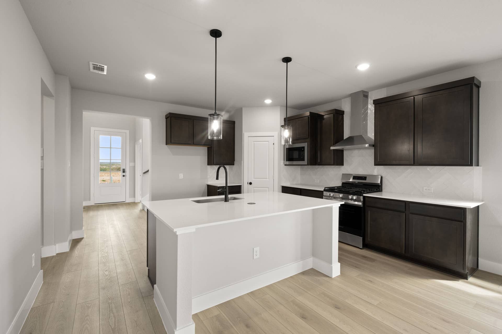 Modern kitchen with dark wood cabinets, island, and pendant lighting.