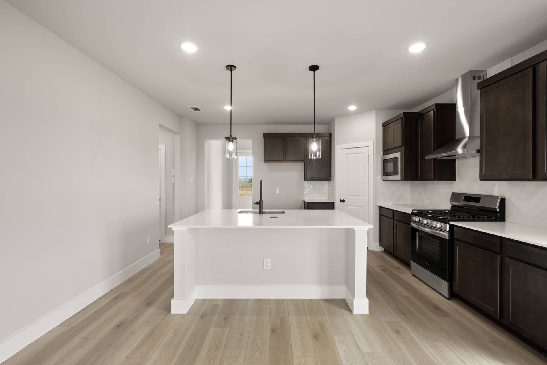 Modern kitchen with island, dark cabinets, and stainless steel appliances.