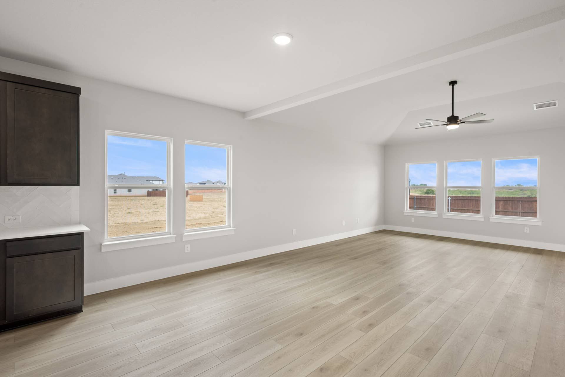 Spacious dining area with large windows and light wood flooring.