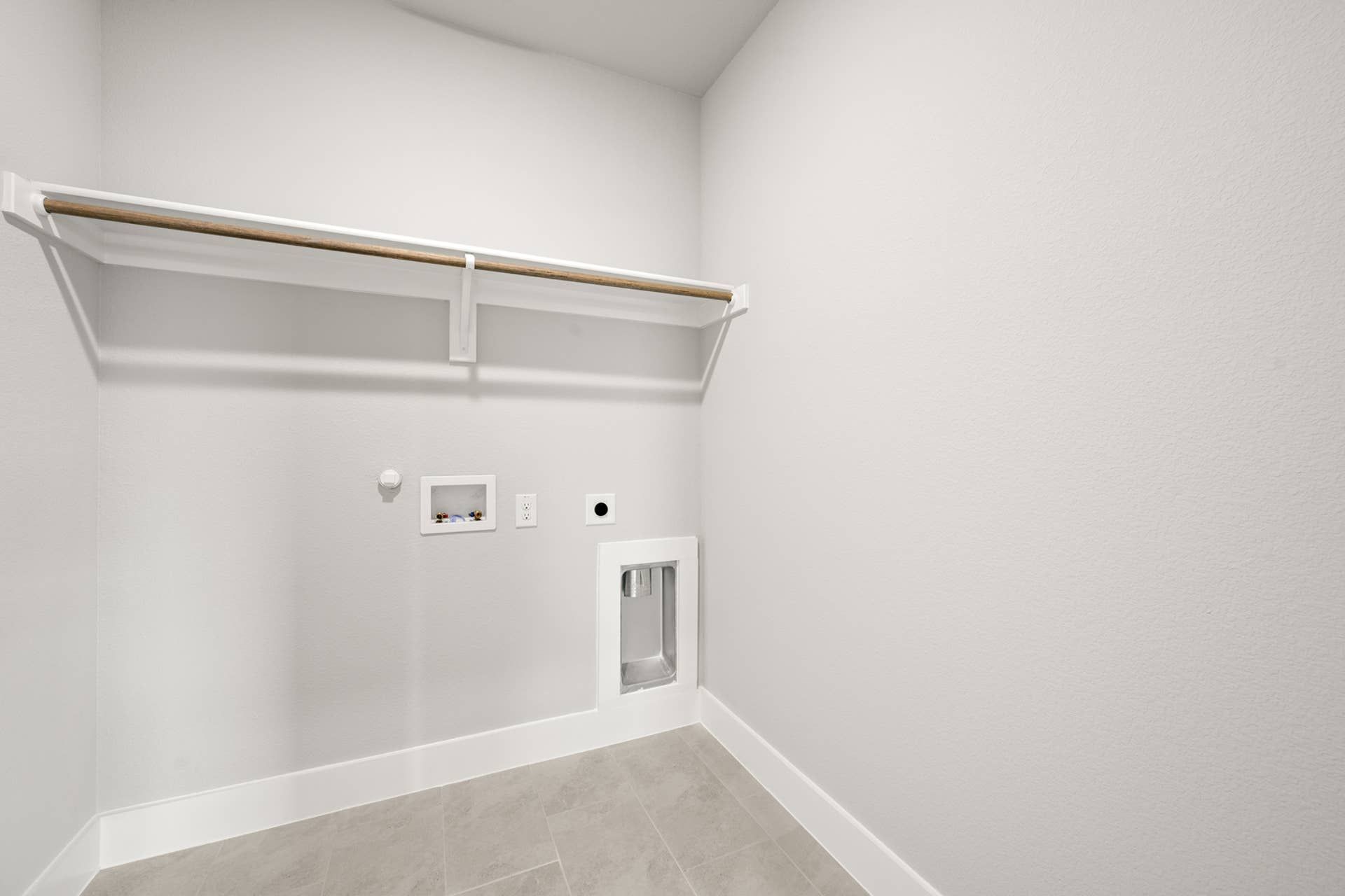 Spacious utility room with hookups and shelving in modern interior.
