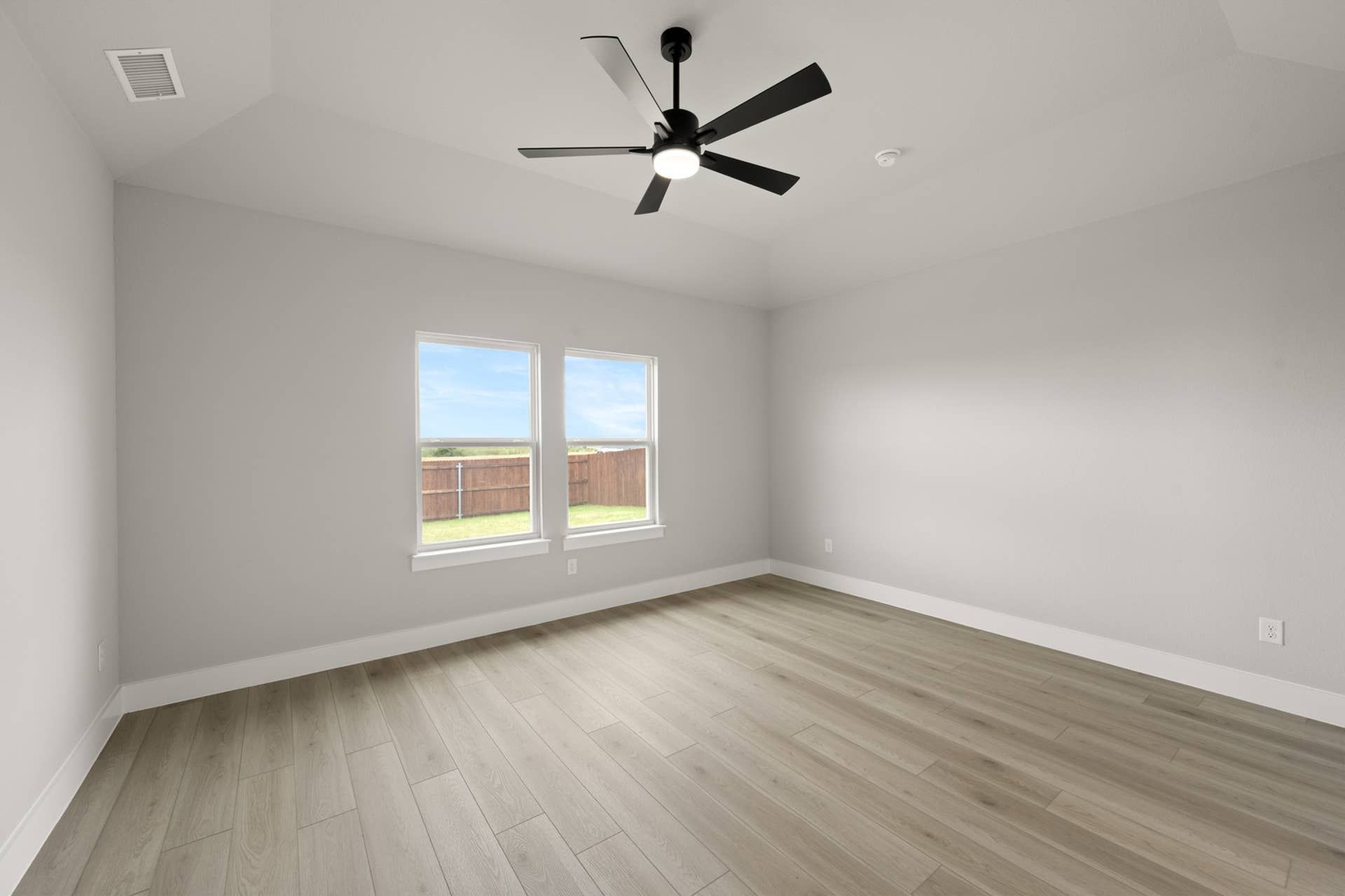 Spacious primary suite with ceiling fan and large windows.