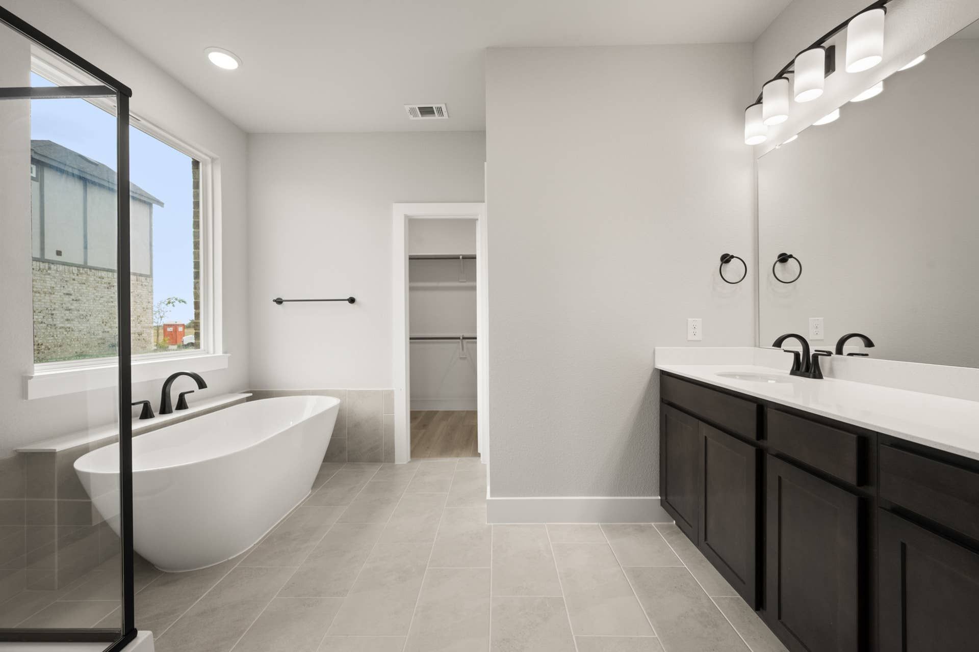 Spacious modern bathroom with freestanding tub, dual sinks, and large window.