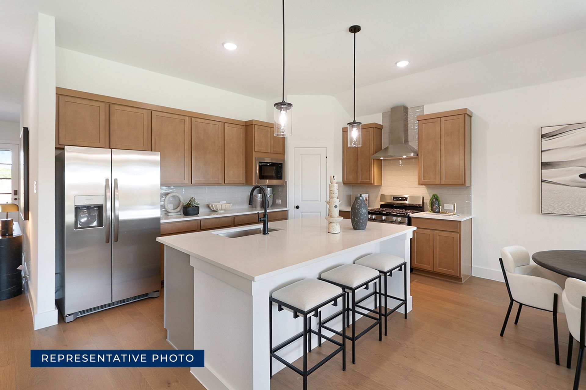 Representative photo of modern kitchen with island, pendant lights, and wooden cabinets.