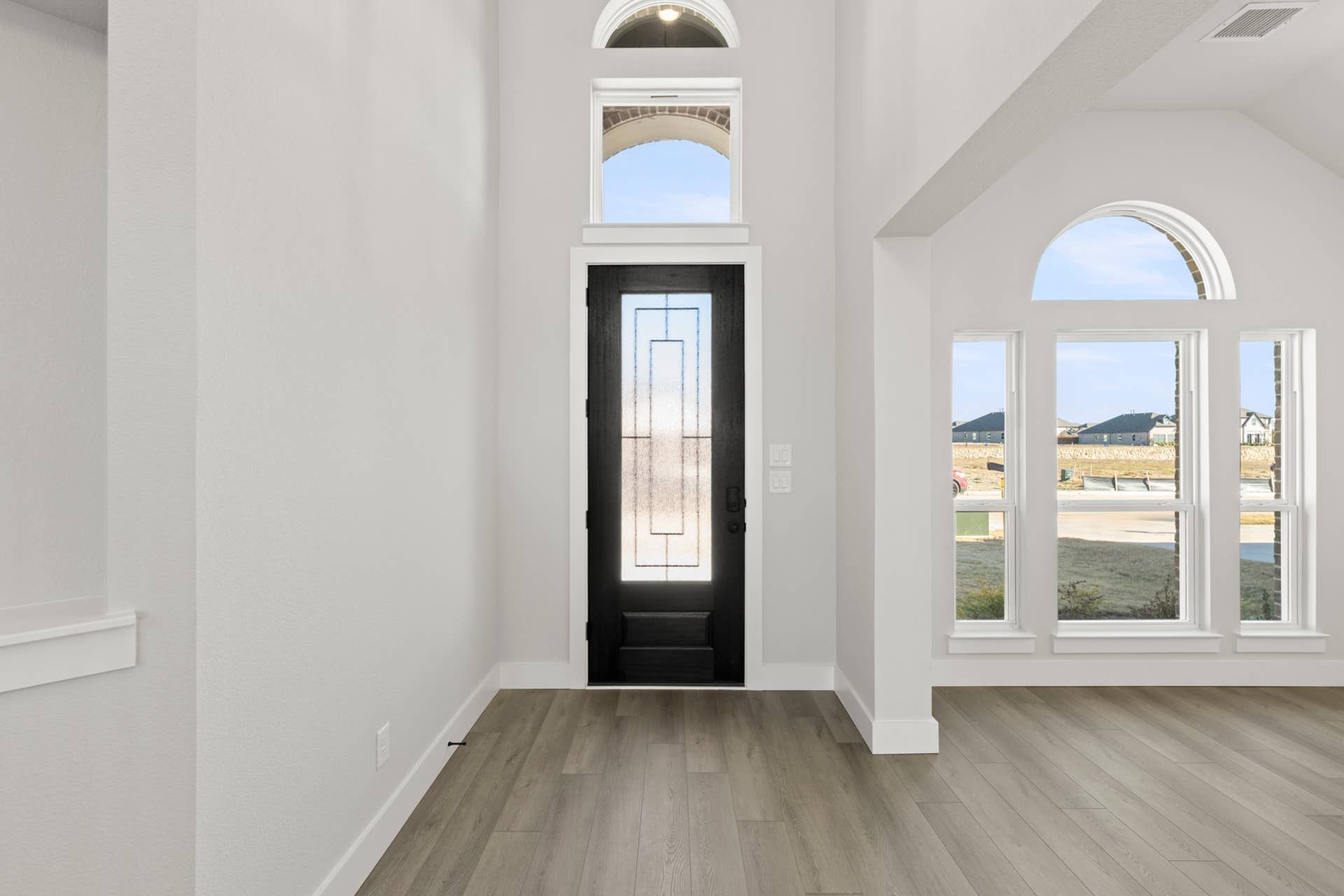 Elegant entryway with modern black door and arched windows.