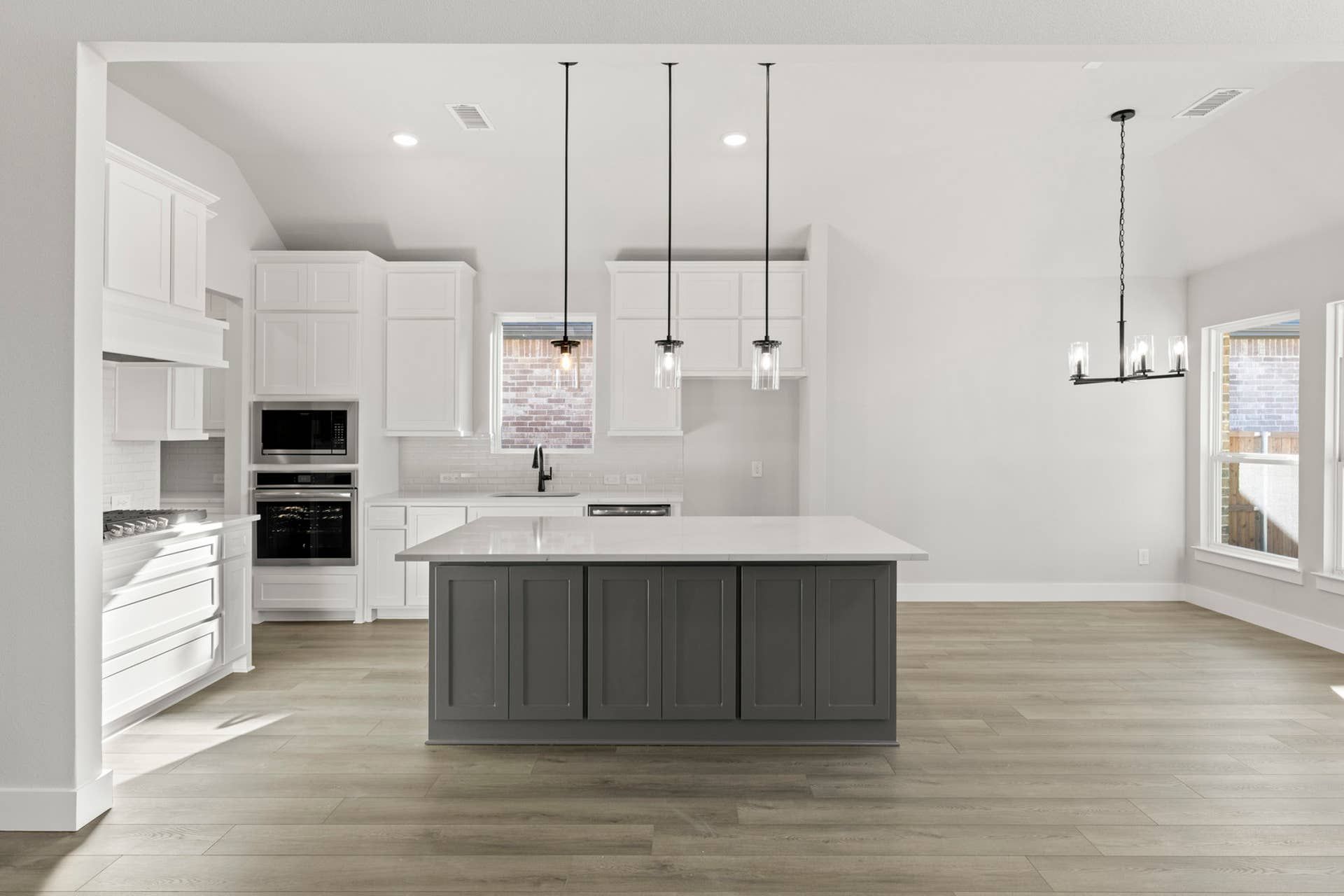 Modern kitchen with island, pendant lighting, and white cabinetry.