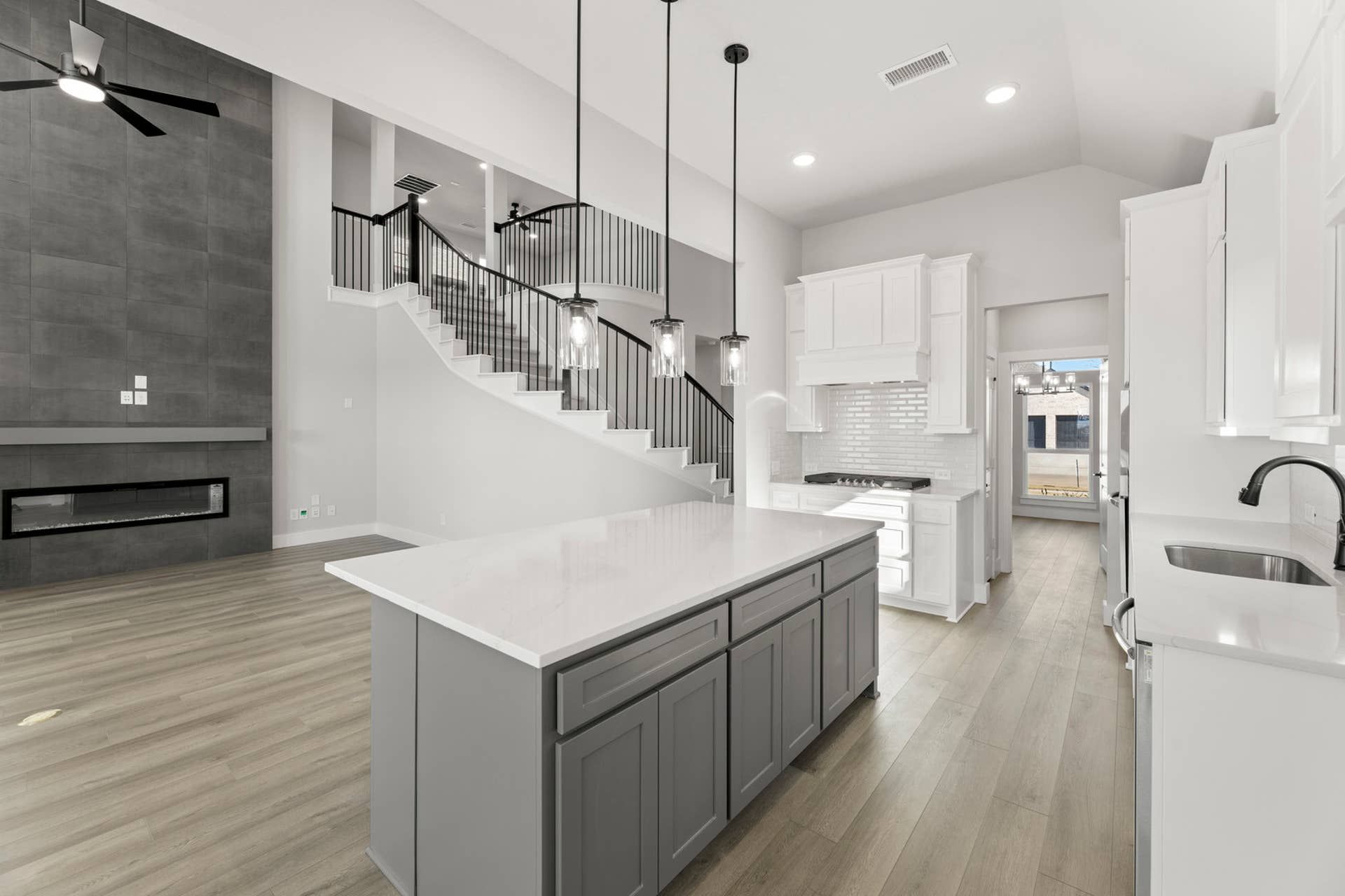 Spacious modern kitchen with large island, pendant lights, and open staircase view.