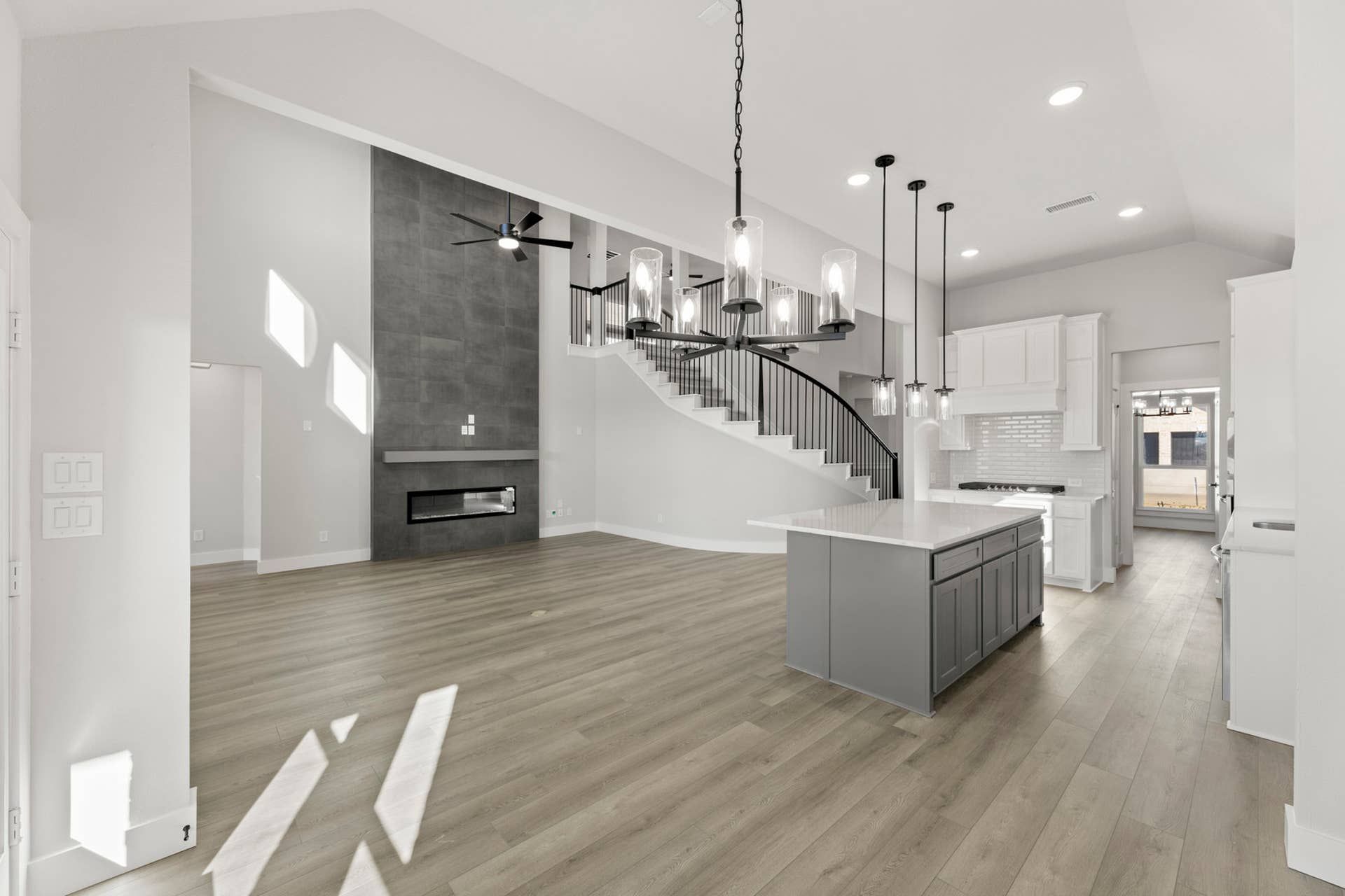 Spacious modern interior with high ceilings, open staircase, and large kitchen island.