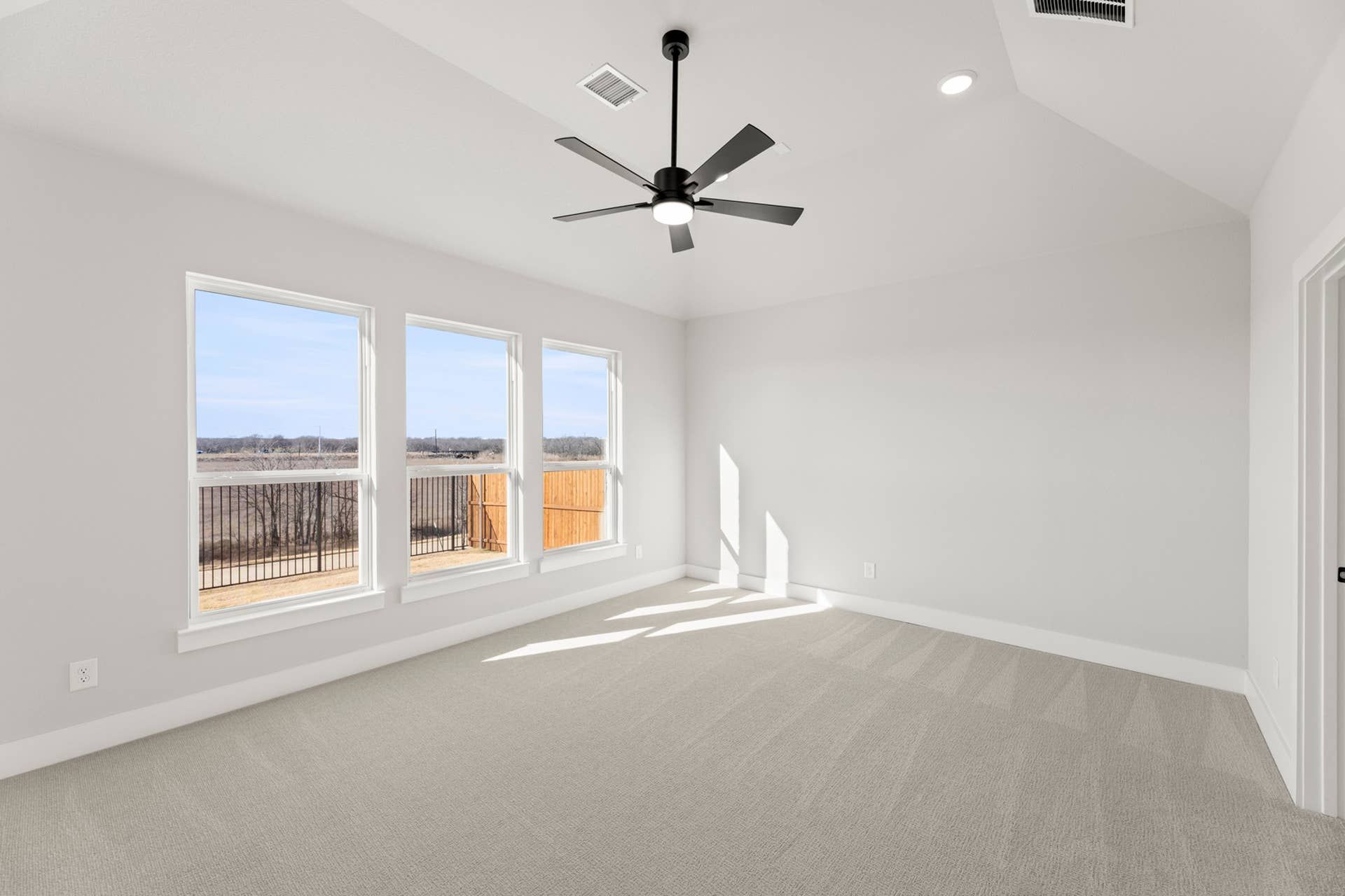 Spacious bedroom with large windows and modern ceiling fan.