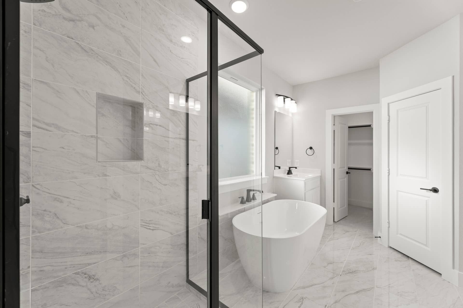 Luxurious bathroom with freestanding tub, glass shower, and marble tile accents.
