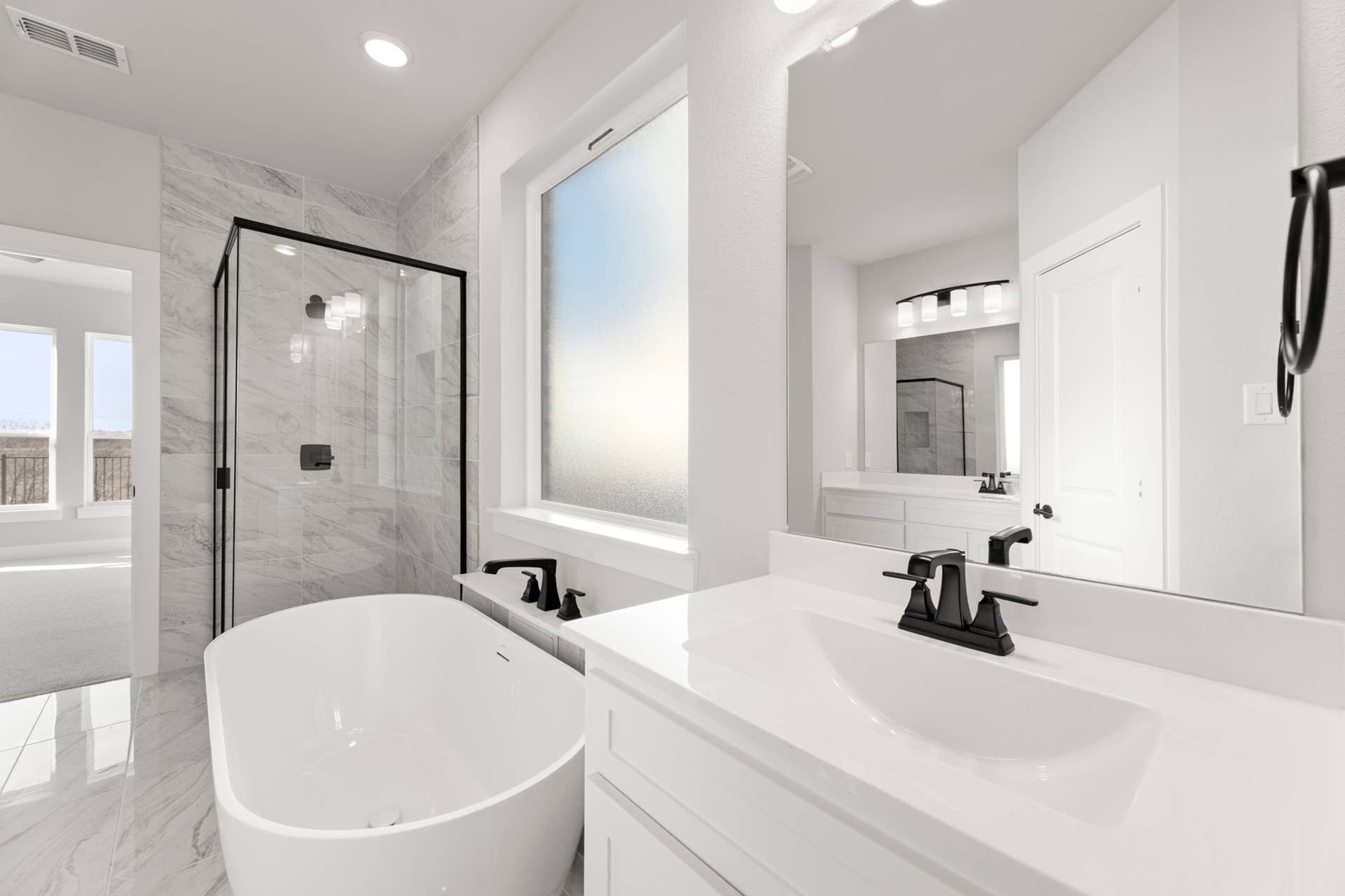 Modern bathroom with freestanding tub, glass shower, and marble tile accents.