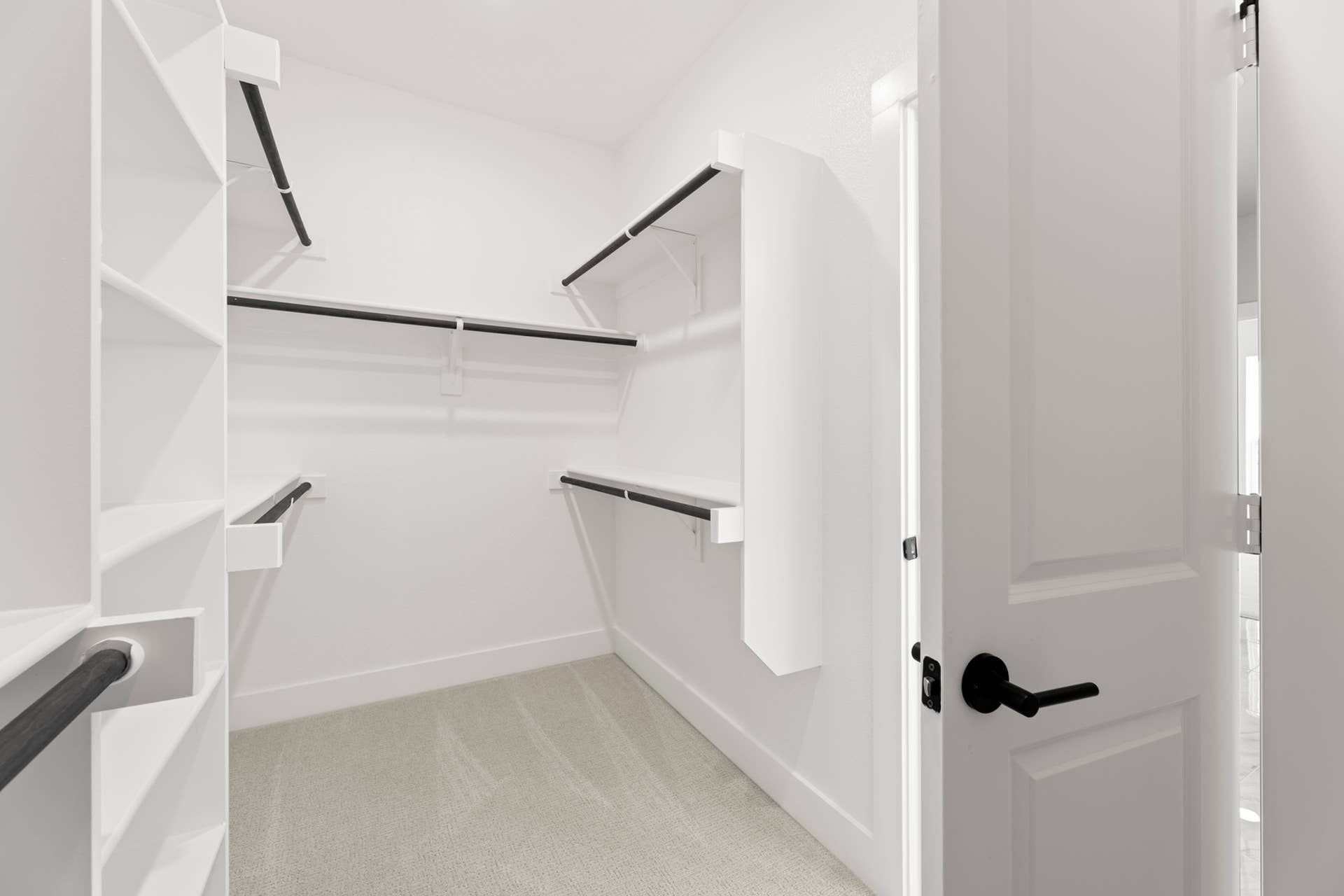Spacious white walk-in closet with multiple hanging rods and shelves.