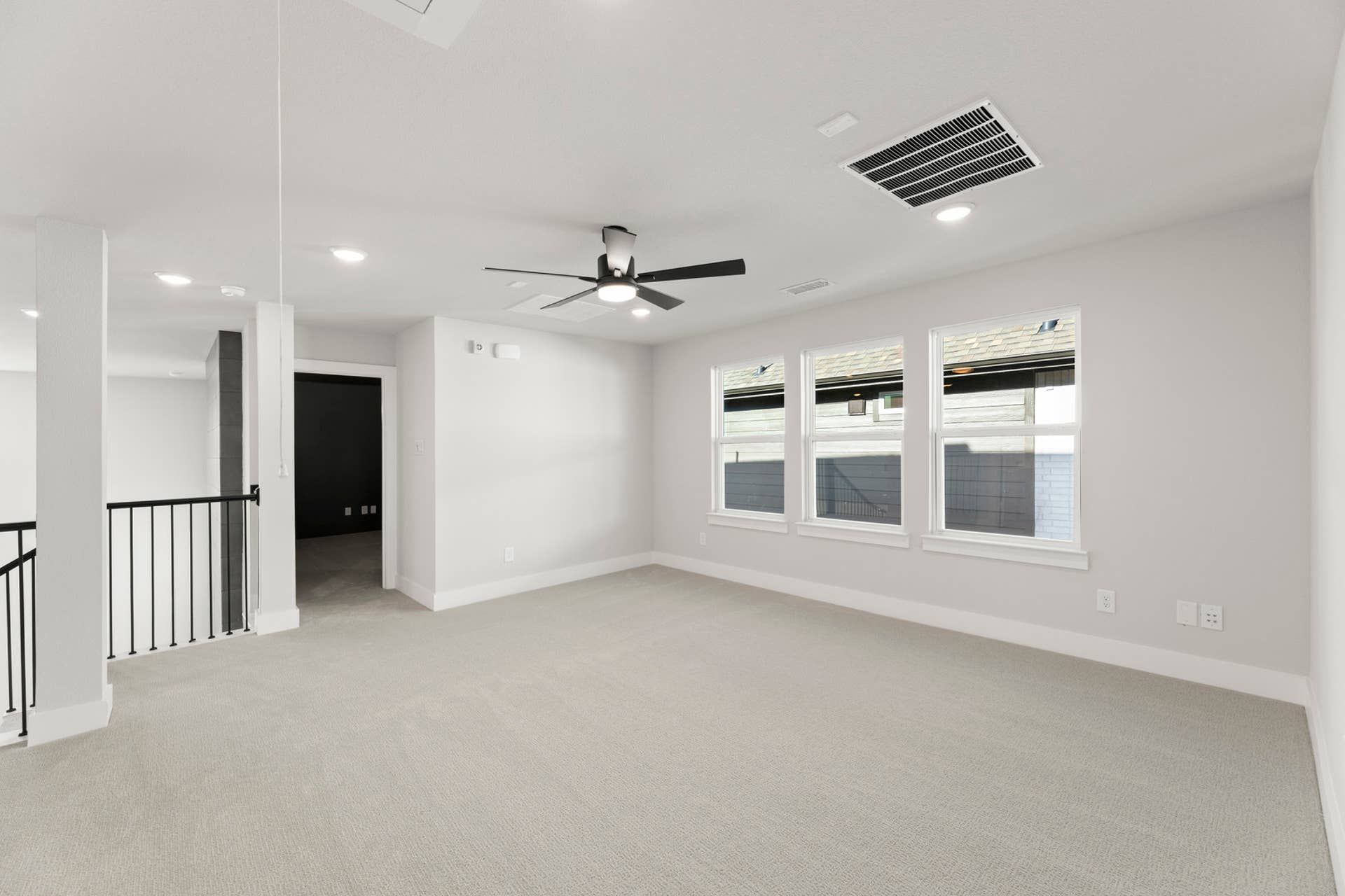 Spacious interior room with carpet, ceiling fan, and natural light through windows.
