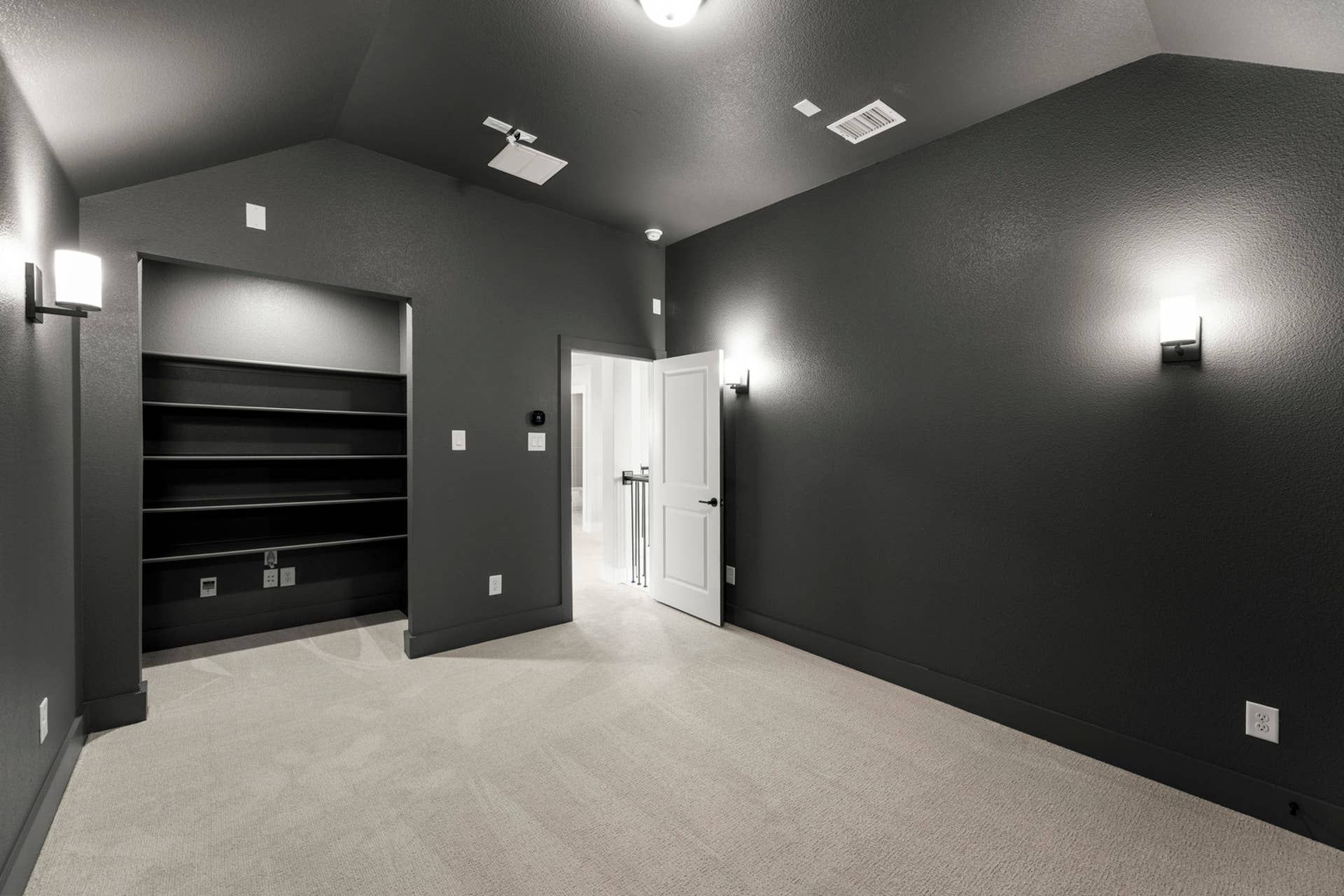 Modern interior room with dark walls and built-in shelving.