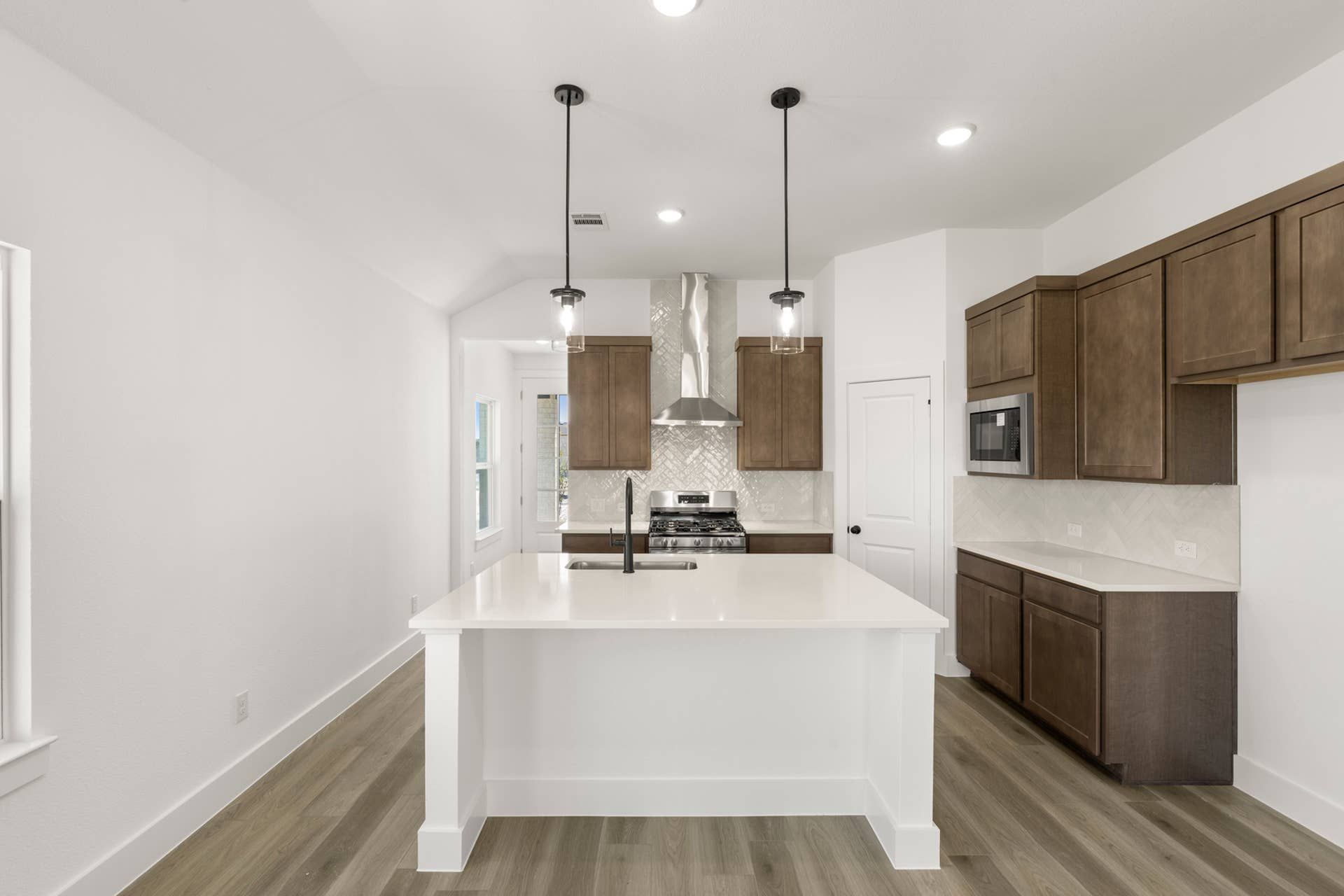 Modern kitchen with wood cabinetry, island, and stainless steel appliances.