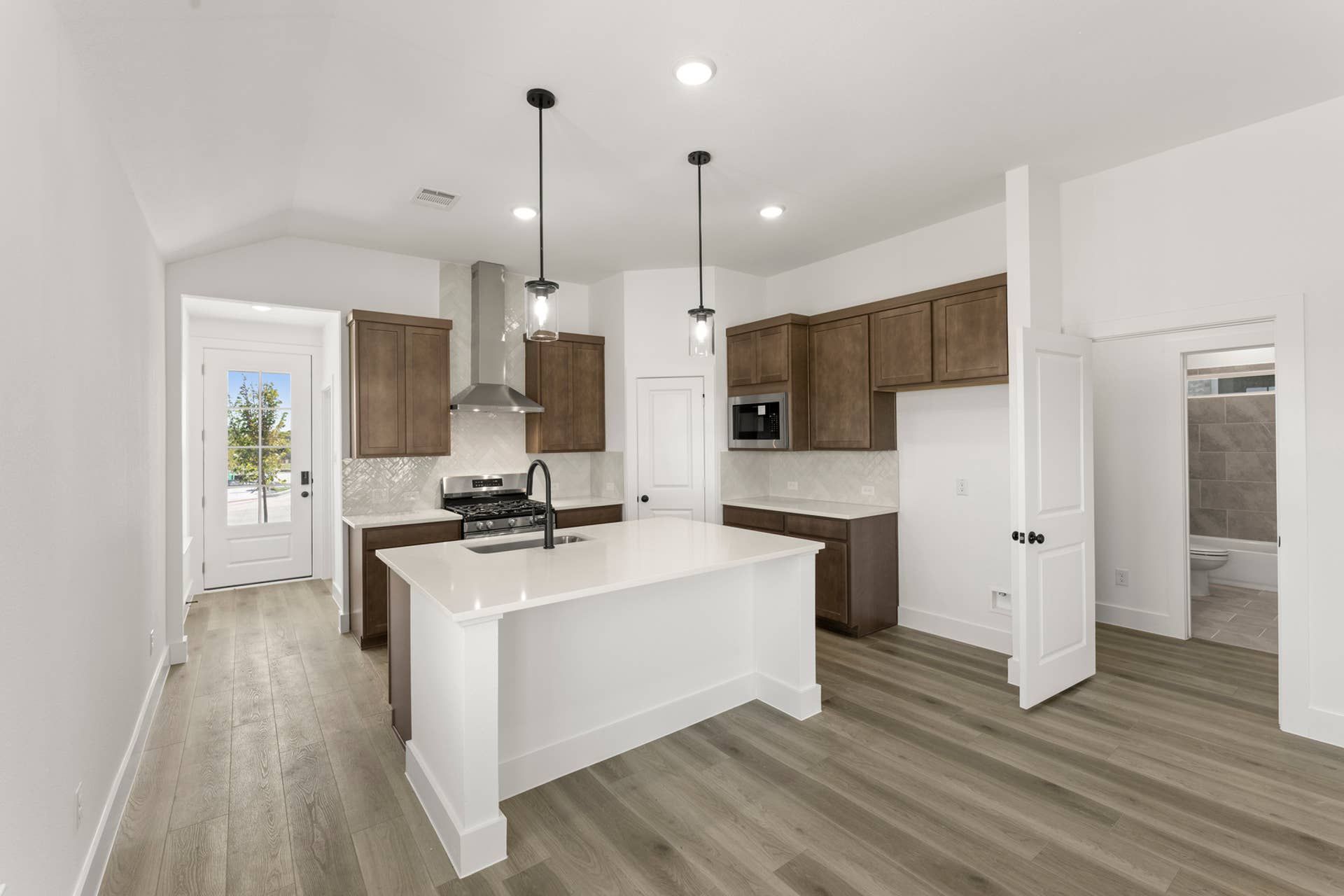 Modern kitchen with island, pendant lights, and wood cabinetry.