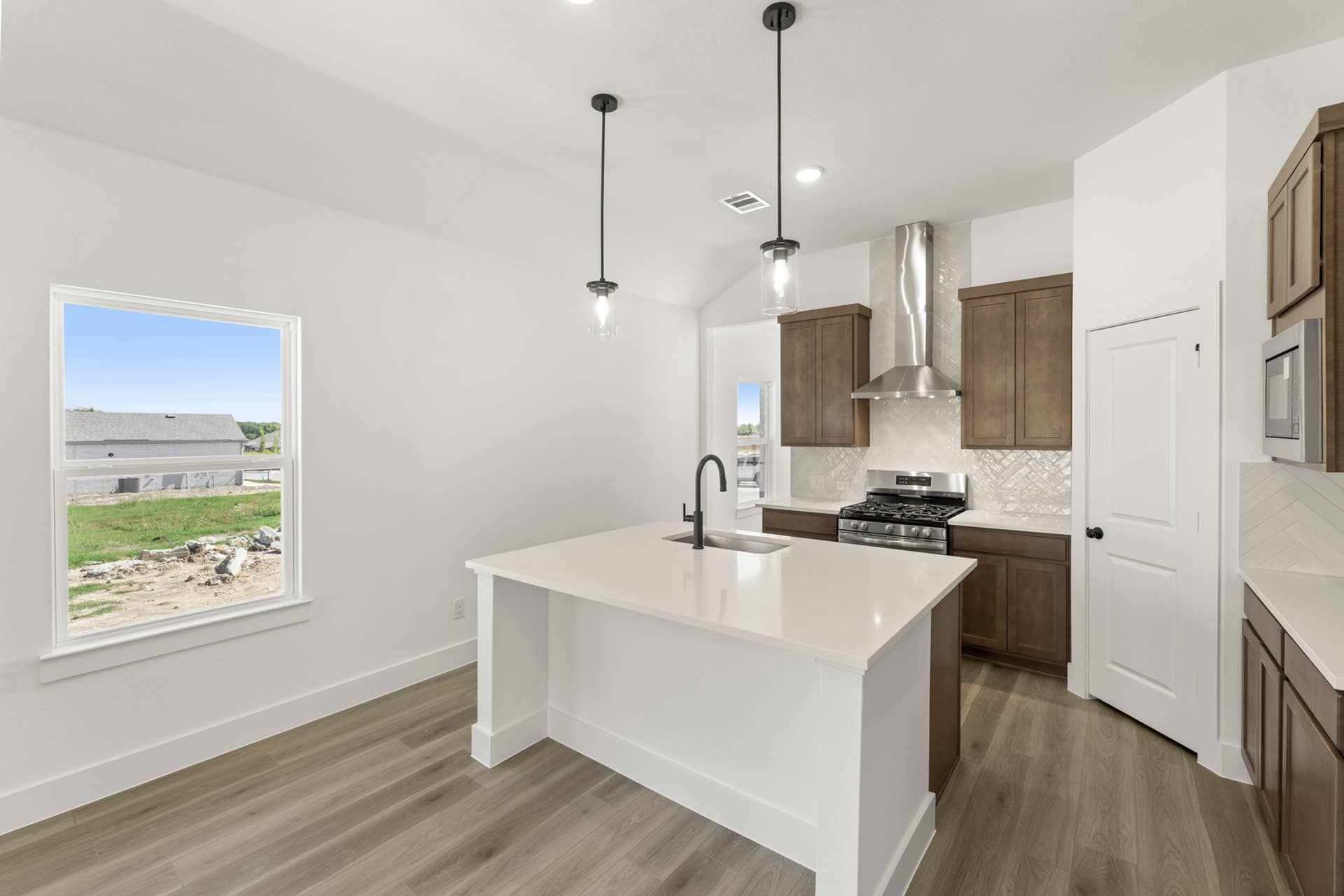 Modern kitchen with white island, pendant lights, and wooden cabinets.