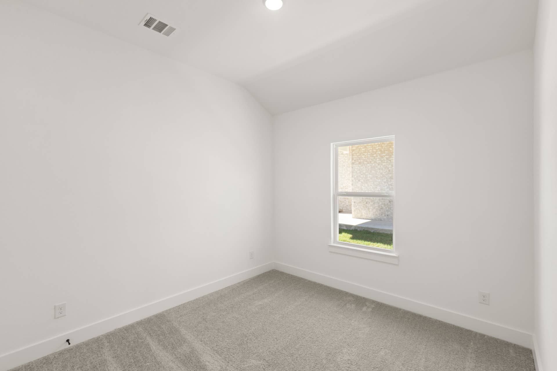 Bright empty bedroom with white walls and carpeted floor.