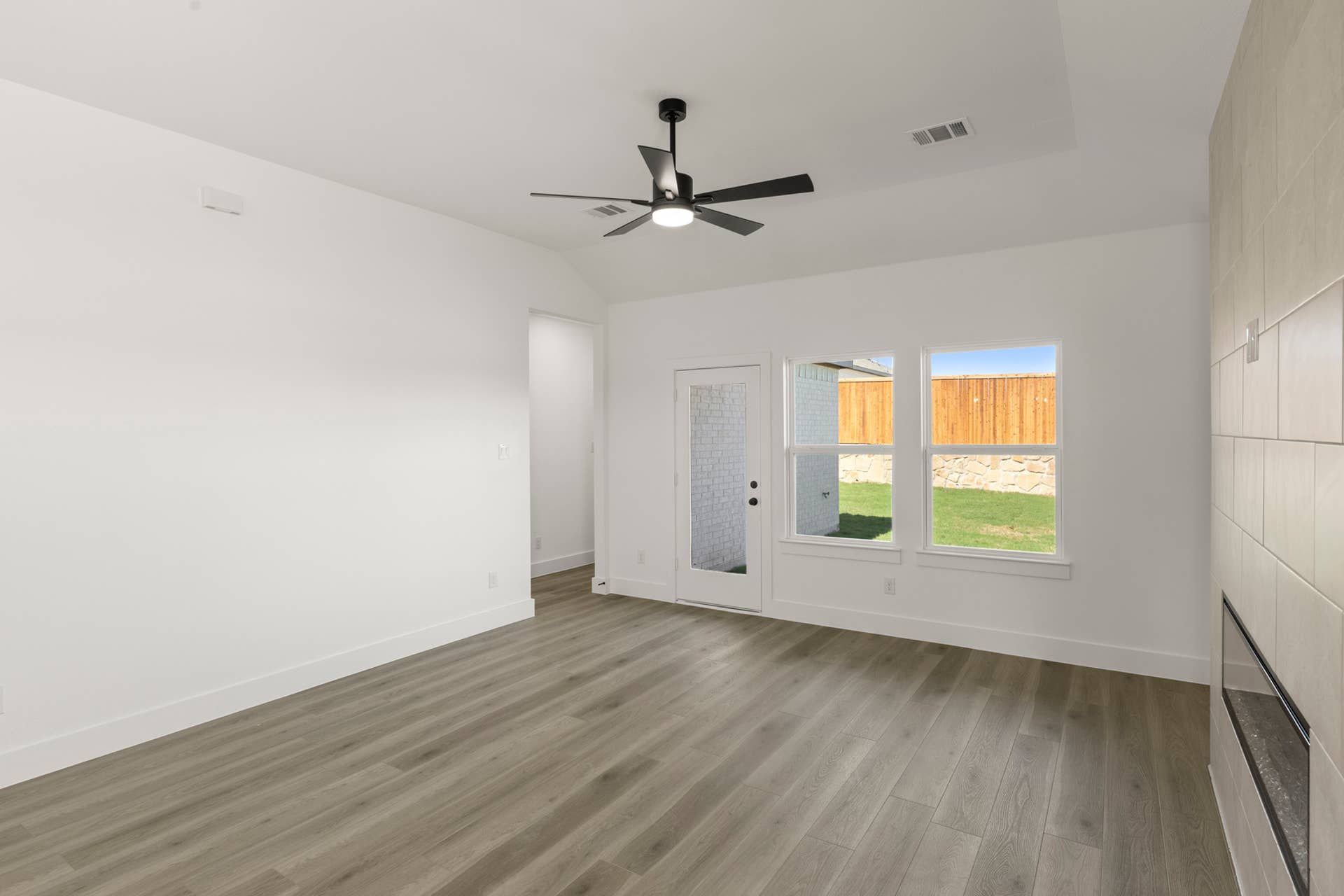 Modern interior with wood flooring, ceiling fan, and large windows.