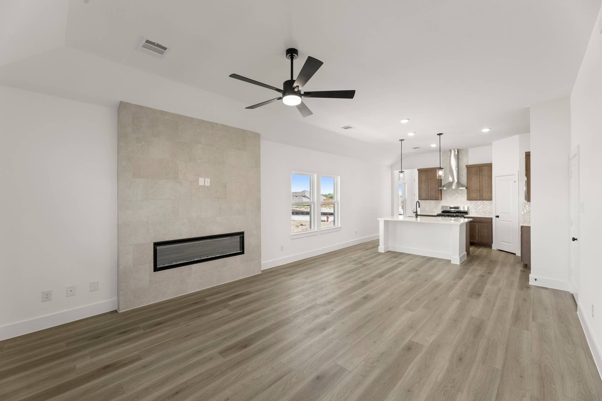 Spacious open-plan living area with modern kitchen and sleek fireplace.