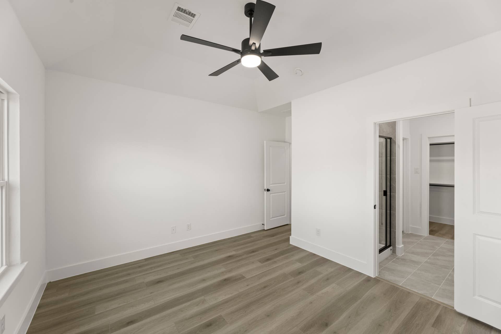 Spacious bedroom with modern ceiling fan and en-suite bathroom access.